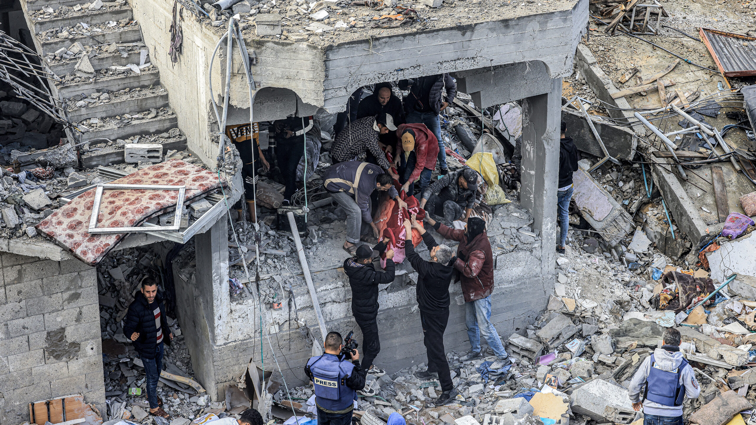 Men recover the body of a Palestinian killed in the aftermath of an overnight Israeli strike at al-Maghazi refugee camp