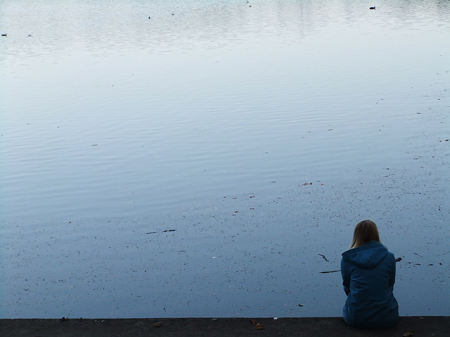 Woman sitting alone near the water