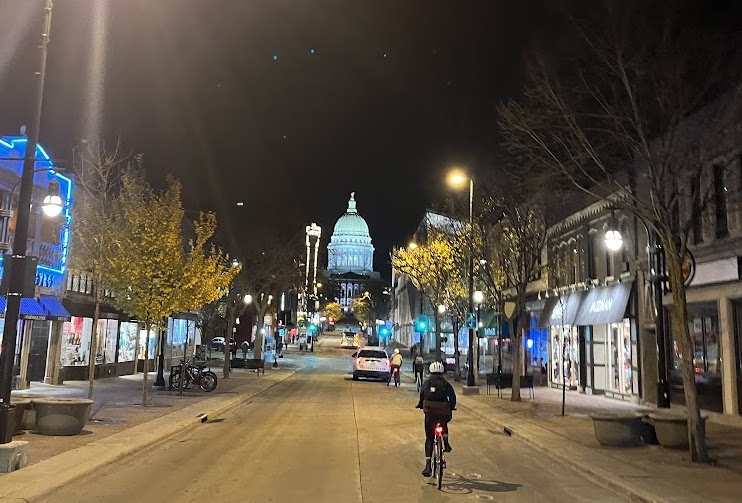 The Wisconsin Capitol seen from a distance from a street with businesses and people