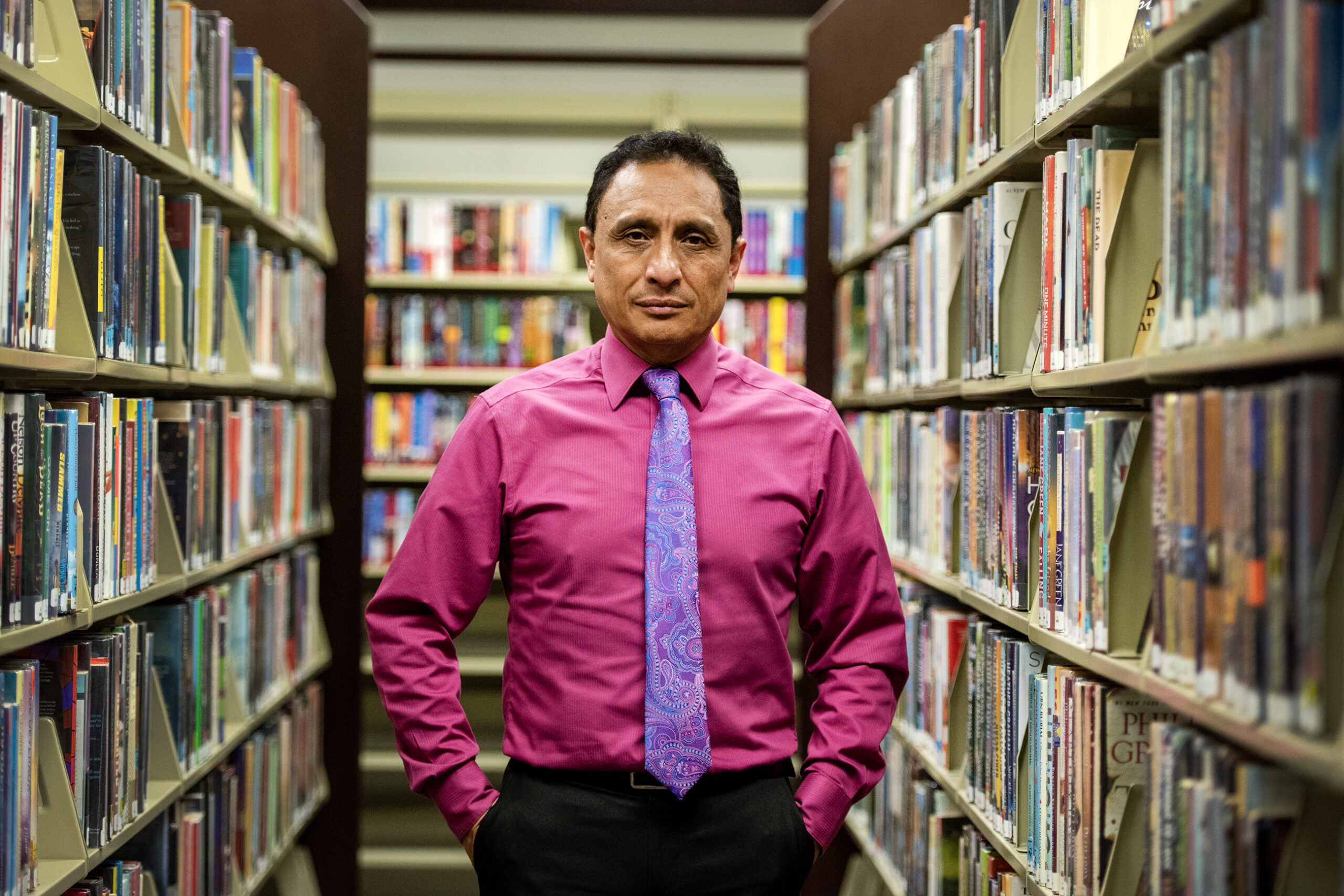 A man stands in between stacks of library books.
