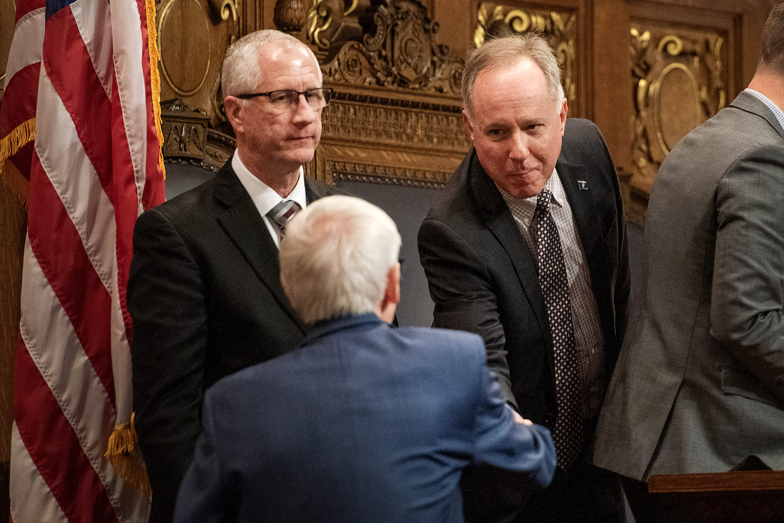 Assembly Speaker Vos leans forward to shake hands with Gov. Evers.