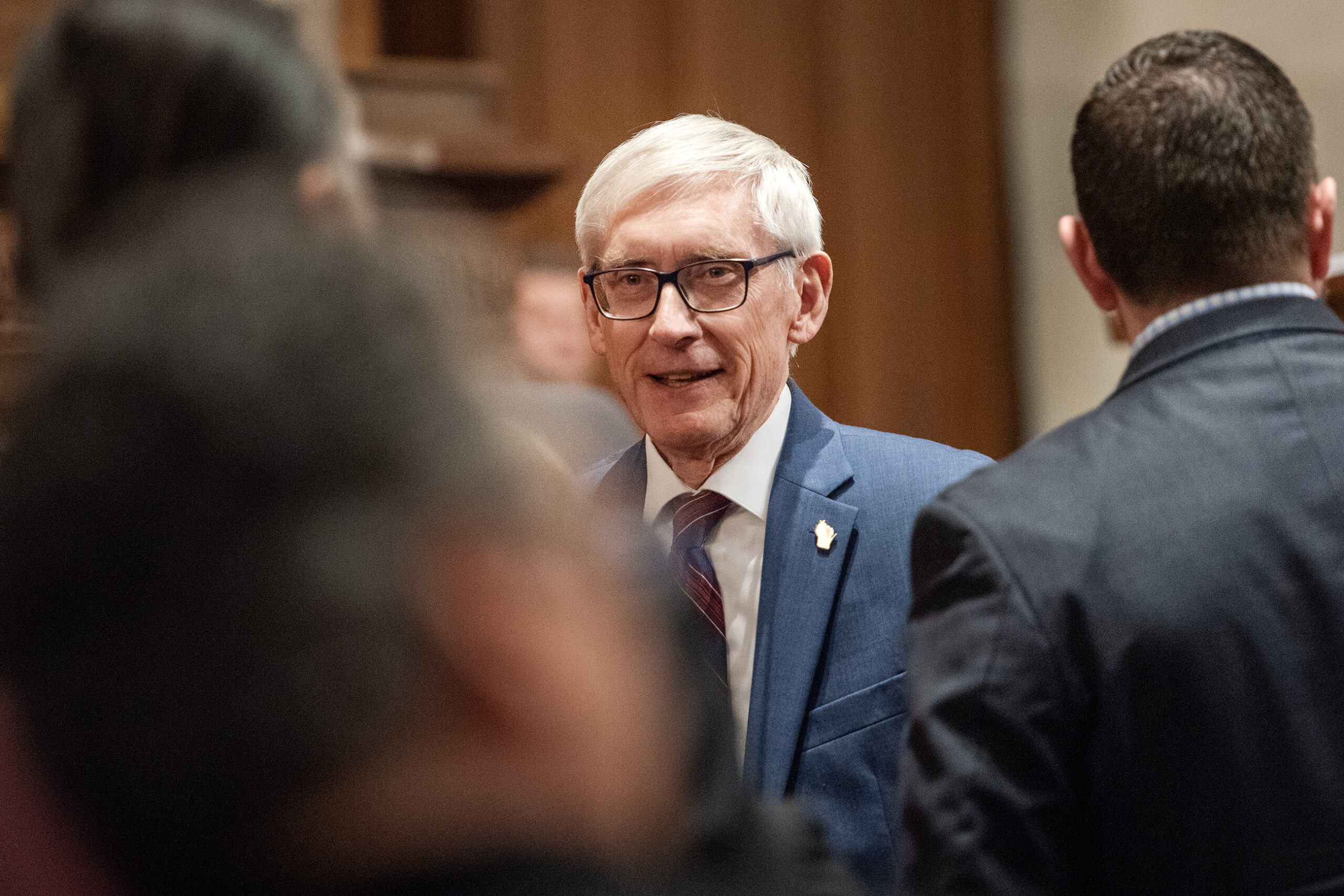 Gov. Evers smiles as he greets lawmakers.