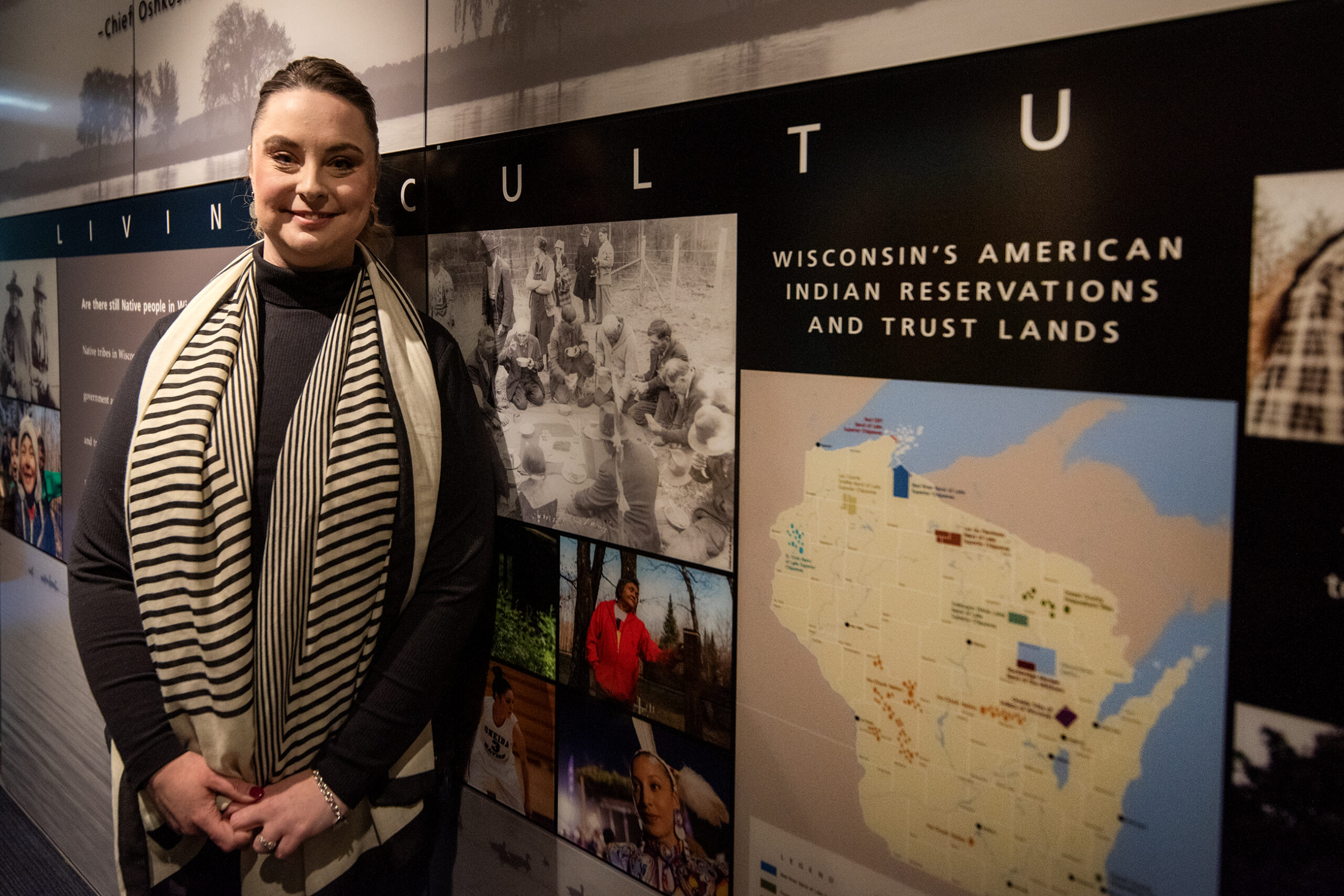 Sarah Phillips stands near a wall that showcases modern Native American culture in Wisconsin.
