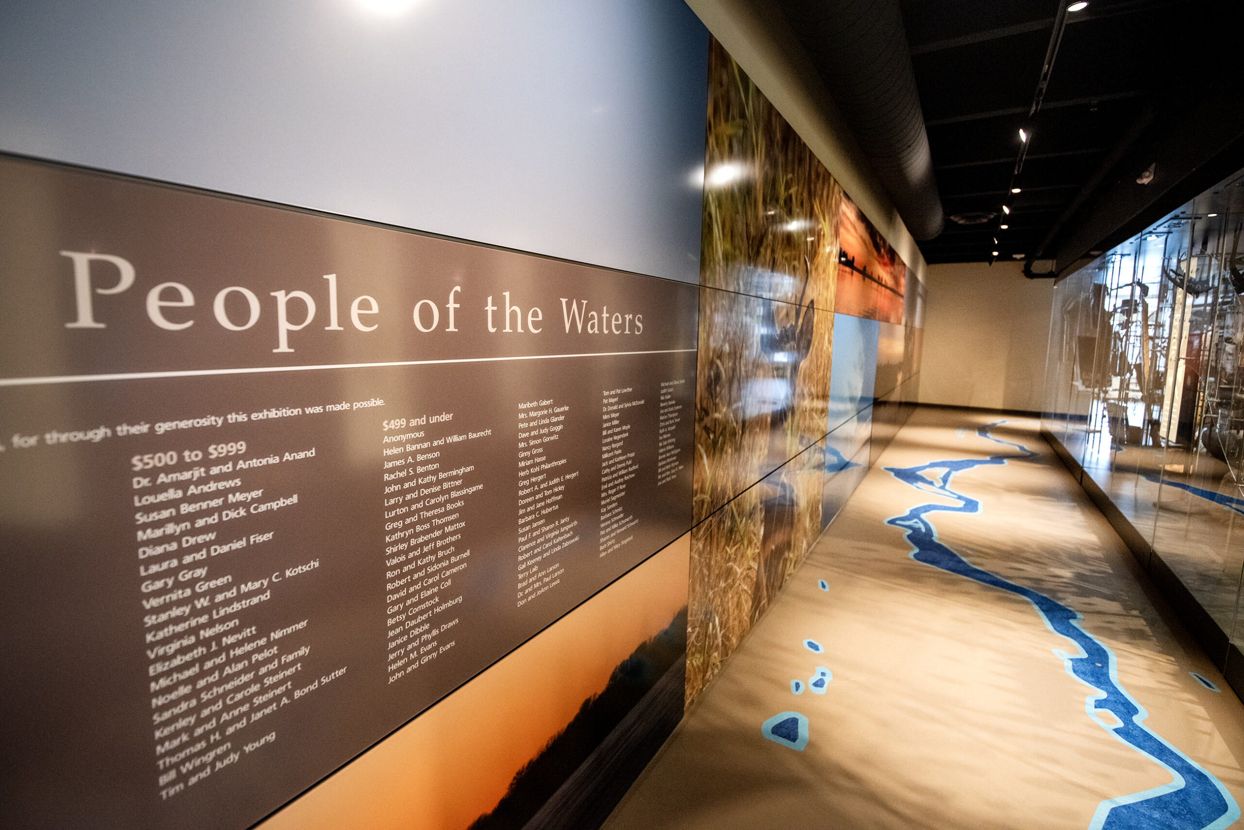 A display says "People of the Water" on the wall. The floor is patterned like a river.