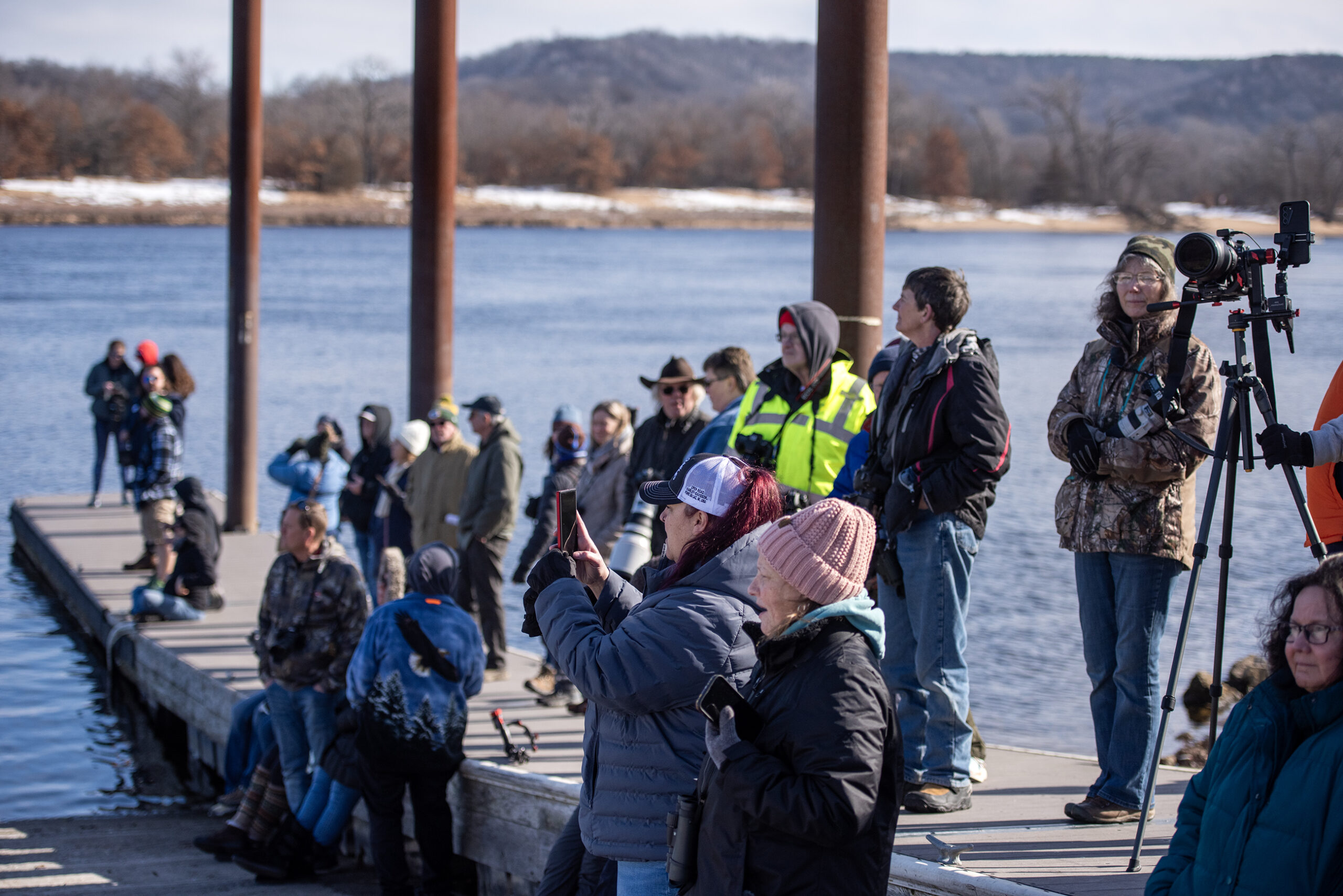 Several people stand on a dock with cameras.