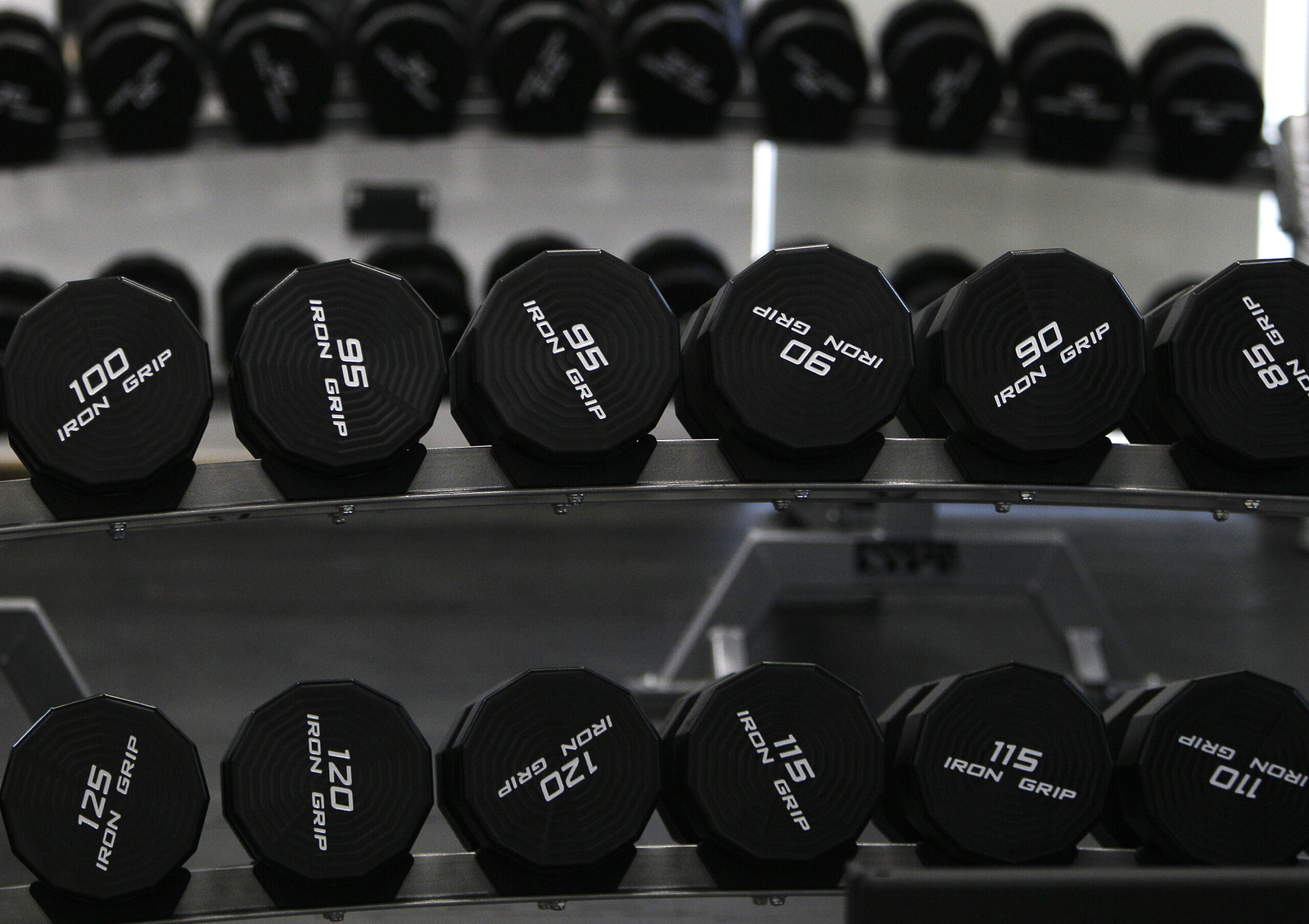 Black exercise weights lined up on a rack.