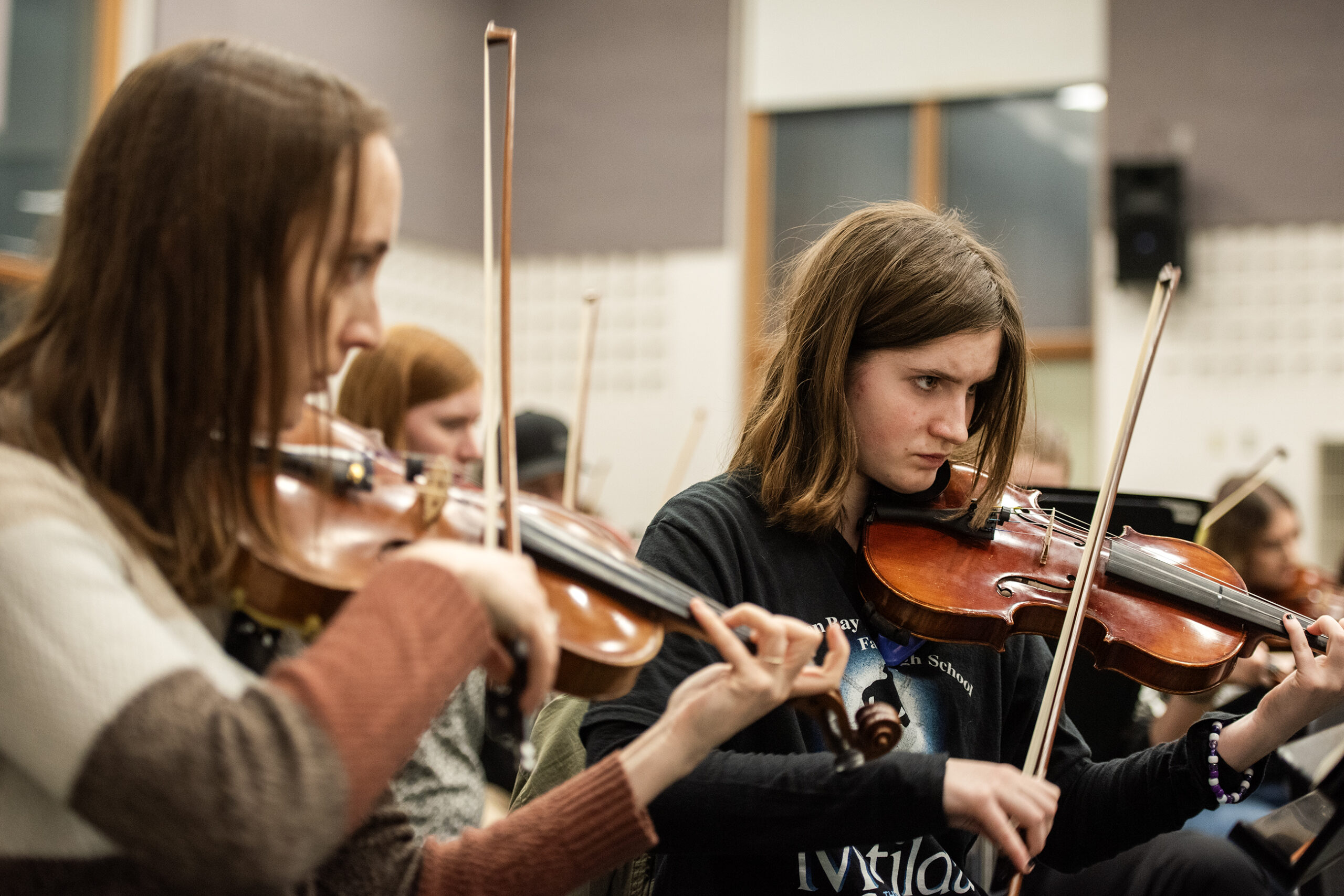 Two violinists concentrate on their playing during practice.