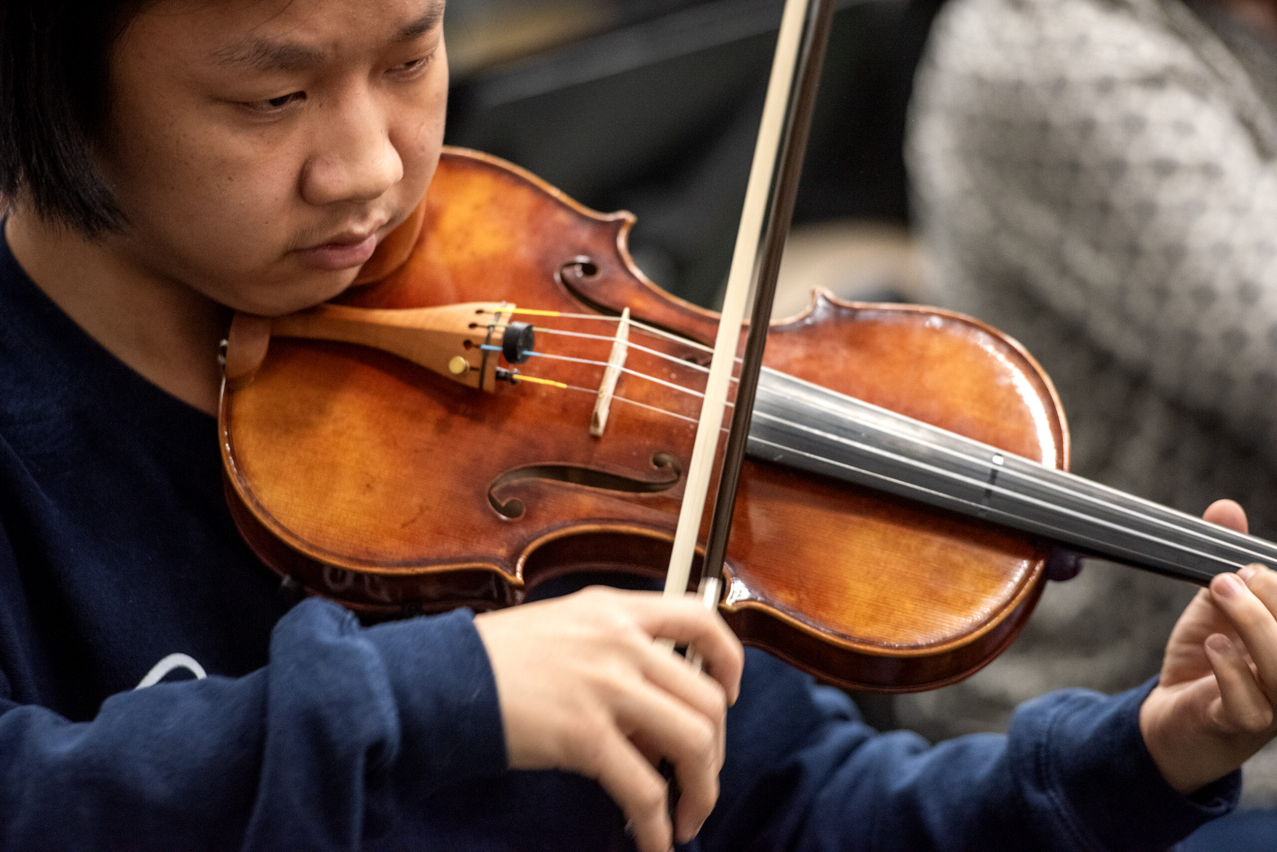 A close up of a violinist looking down at the strings of her instrument.