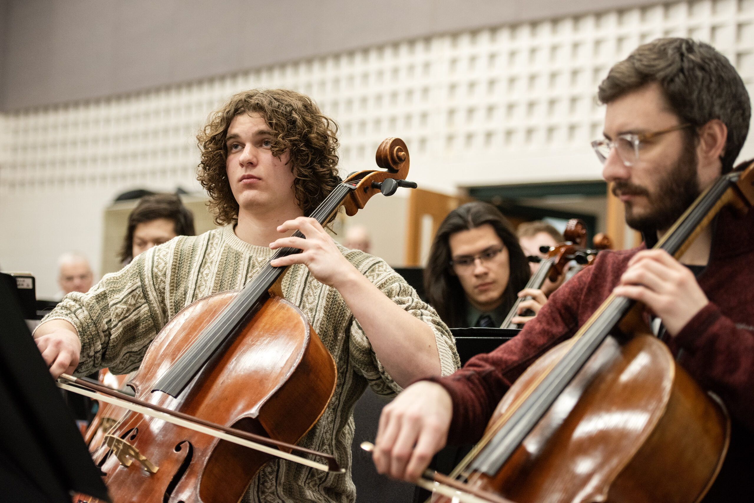 Two musicians play the cello during practice.