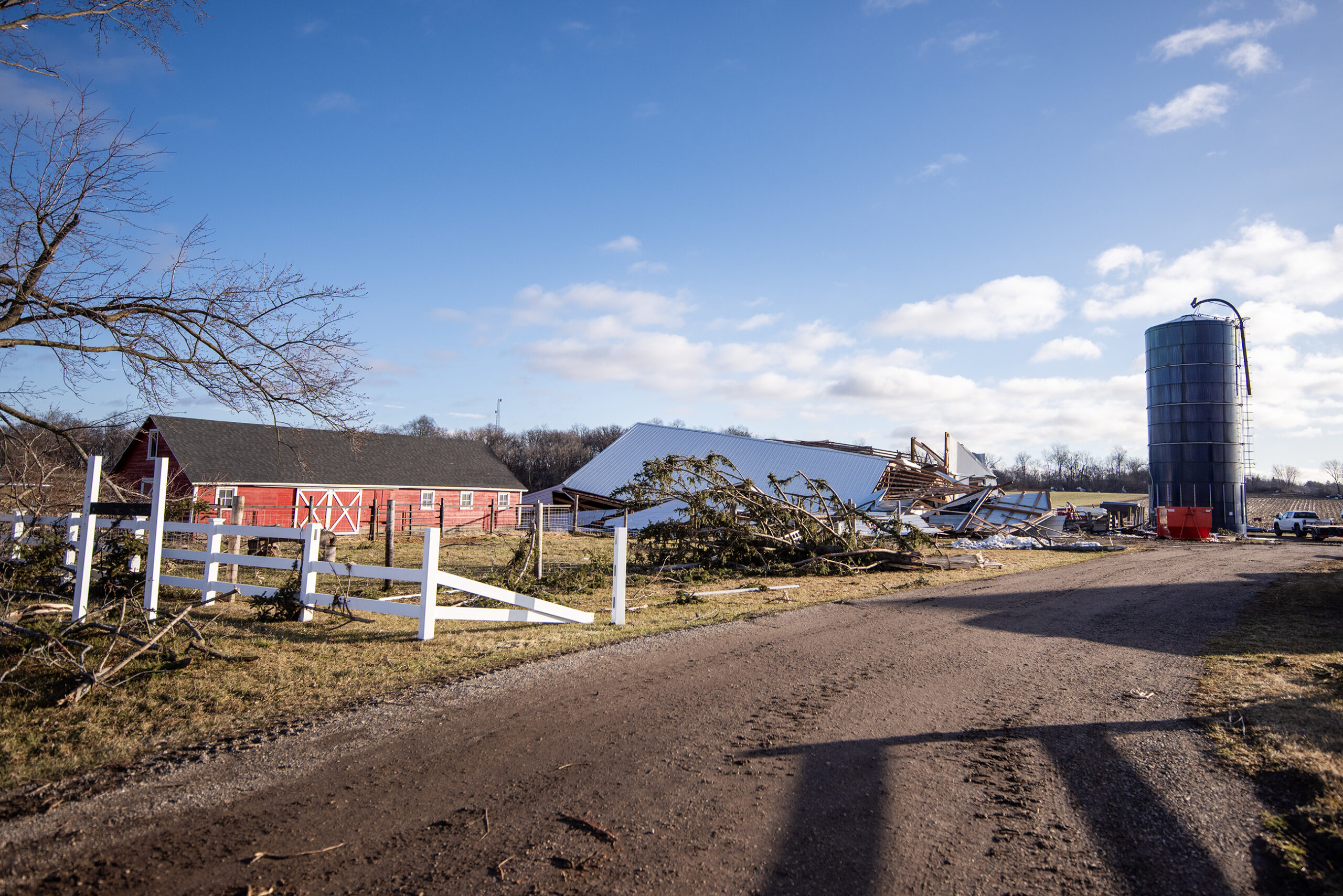 A barn is completely torn down near a damaged fence.