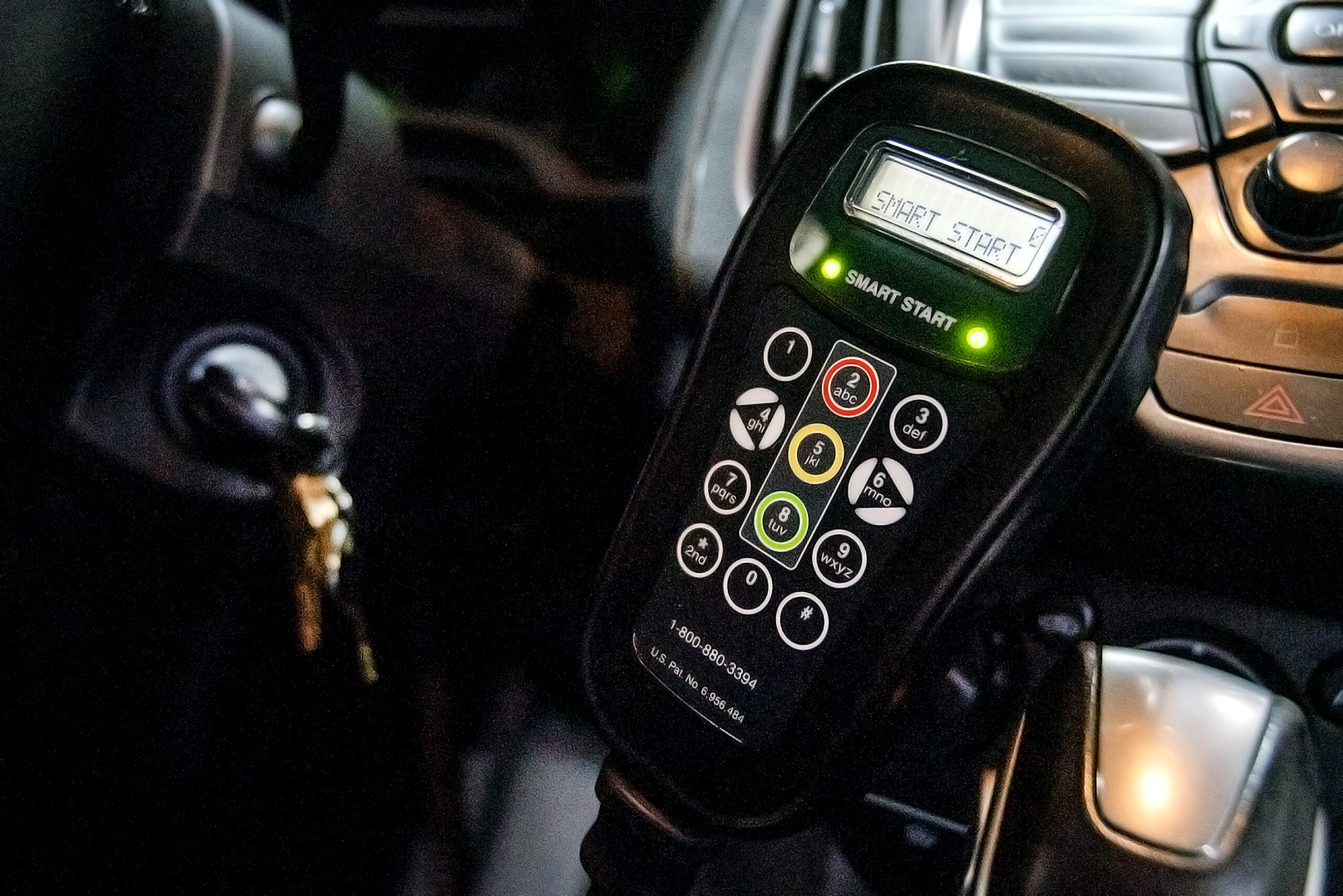 A device with a keypad and a screen is installed near the ignition of a car.