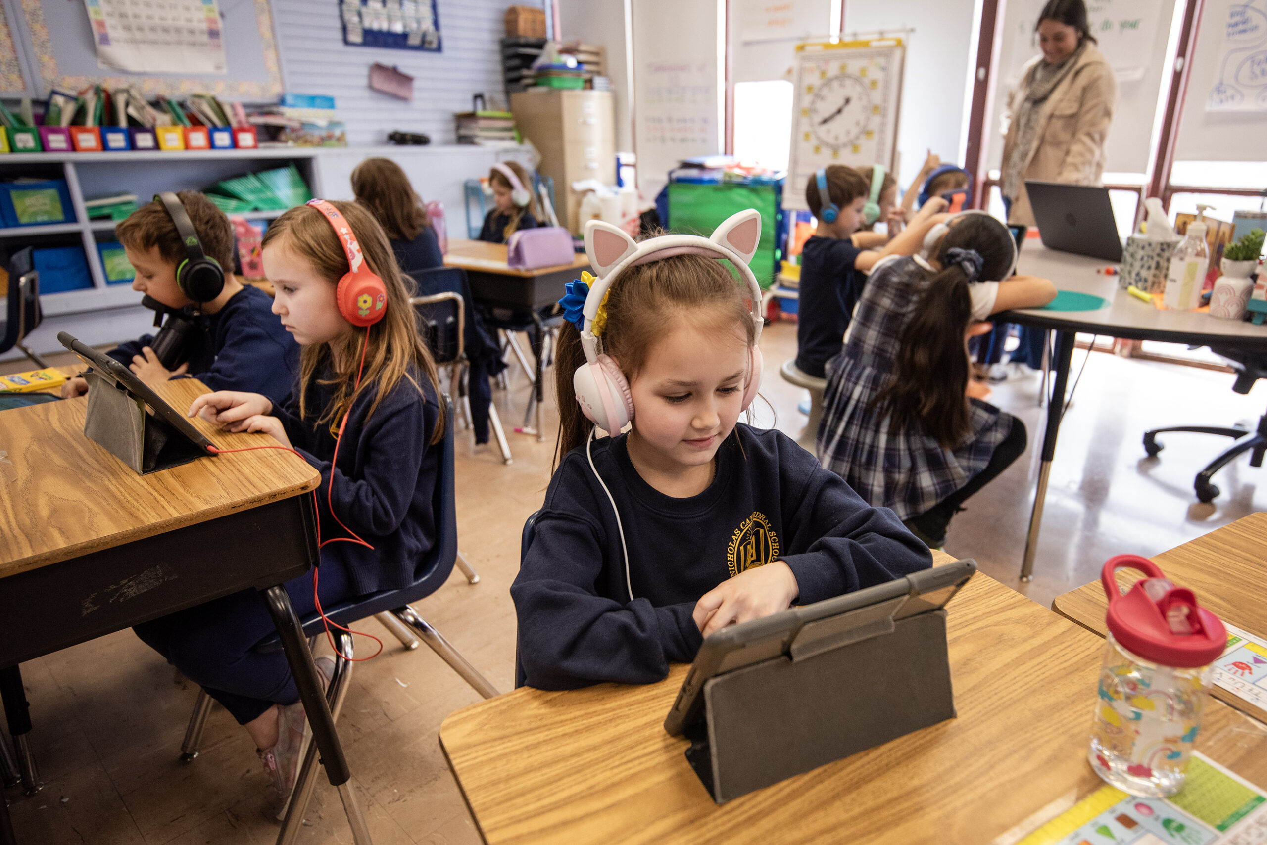 A student with headphones watches a tablet.