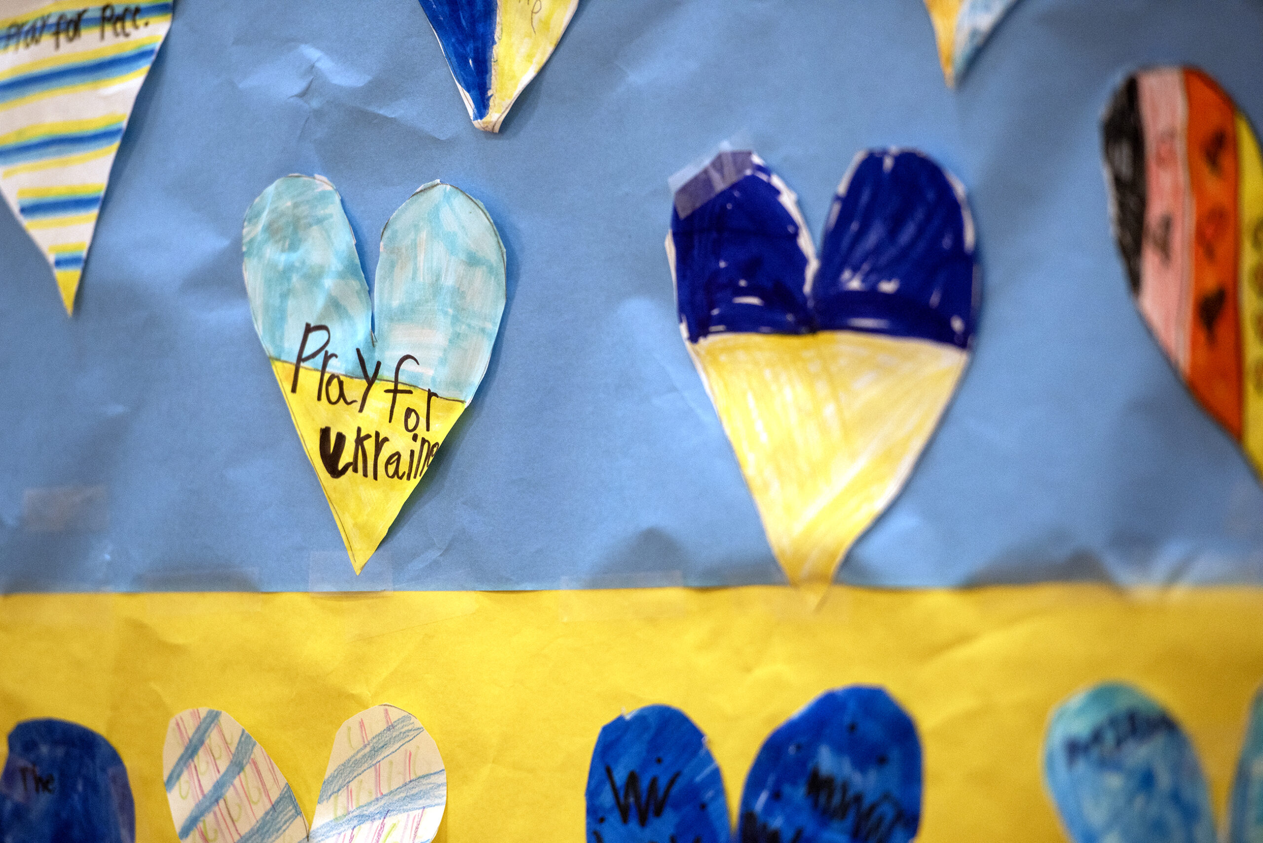 A paper heart is colored in blue and yellow, saying "Pray for Ukraine."