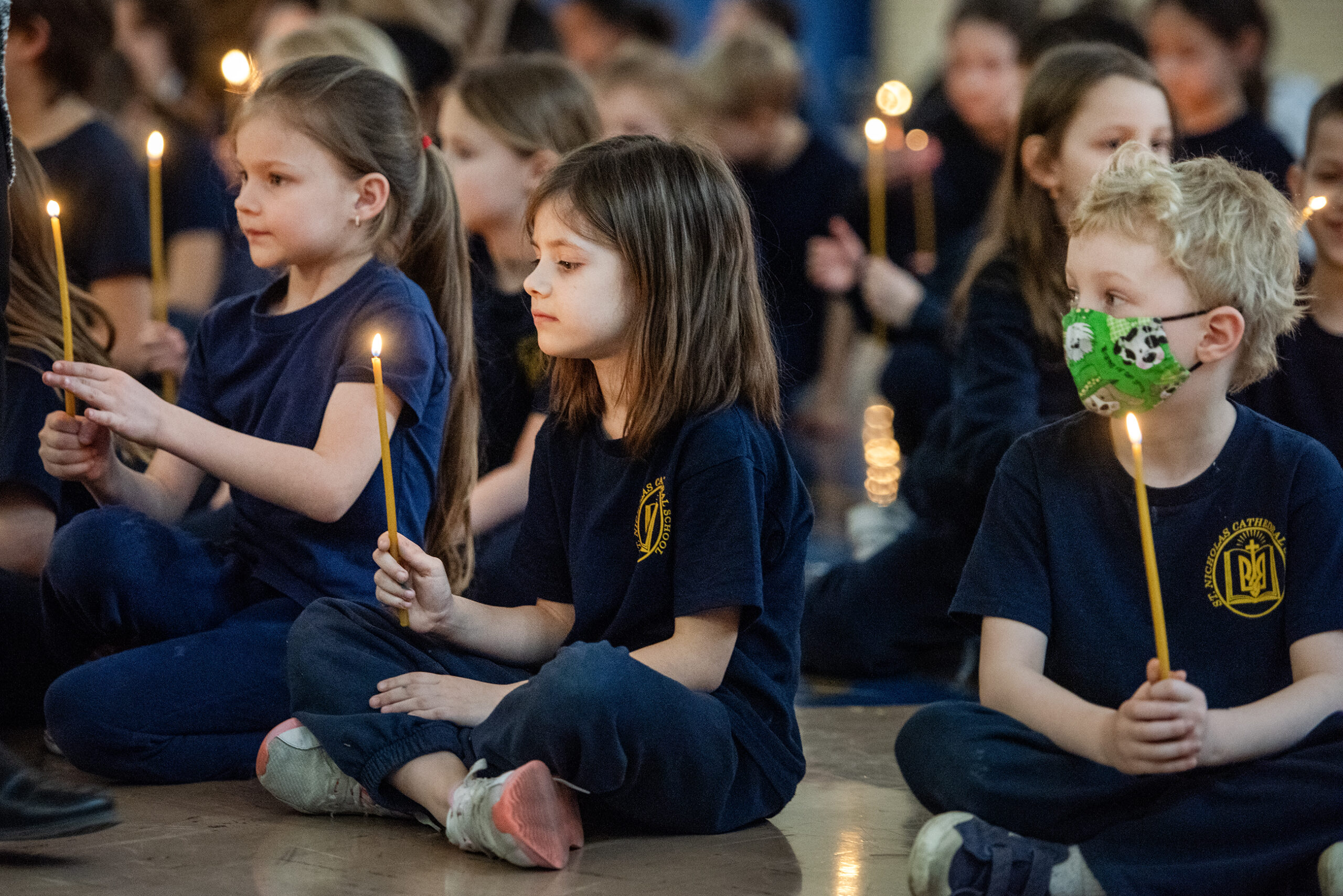 A group of children sit with lit candles.