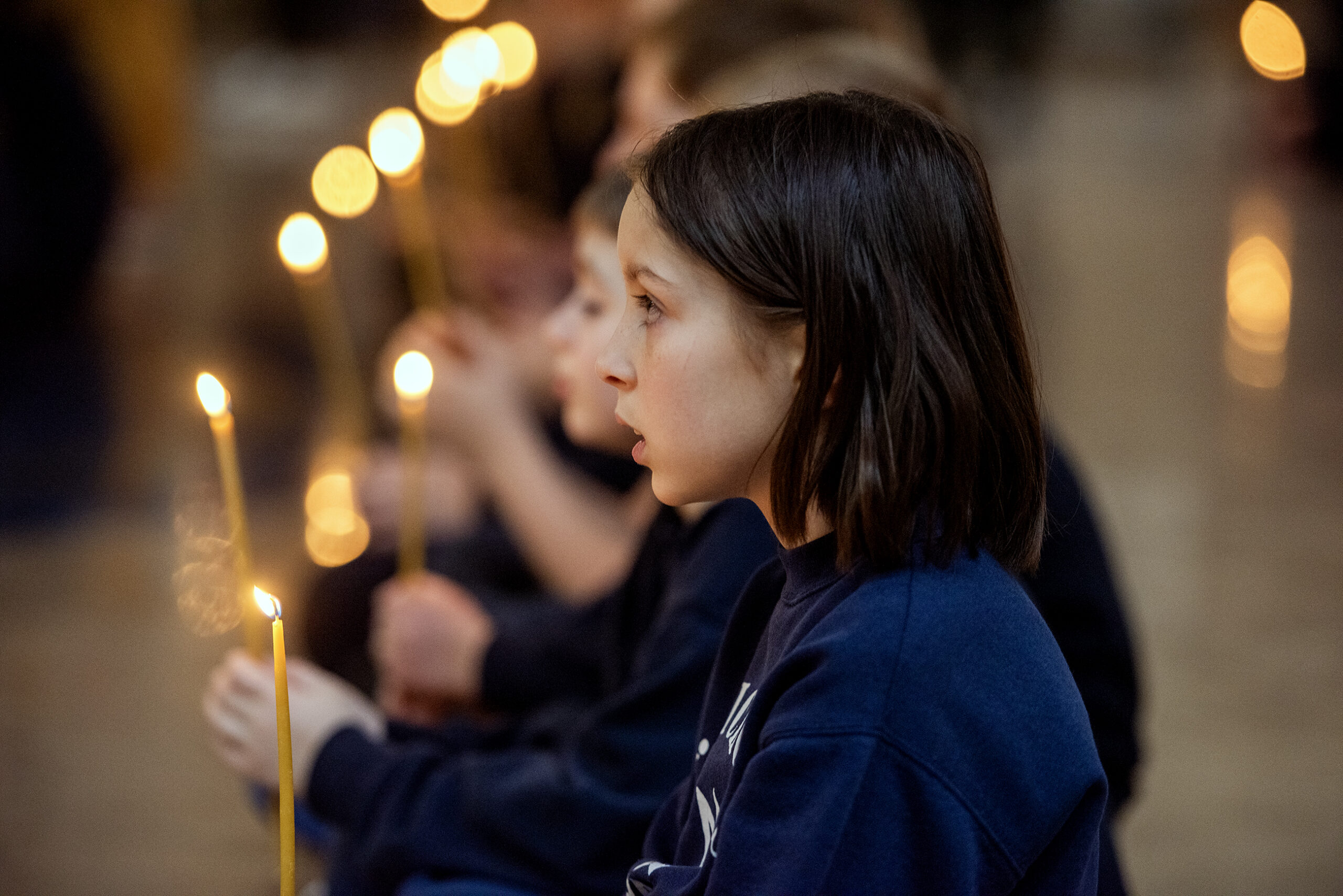 A girl holds a lit candle.