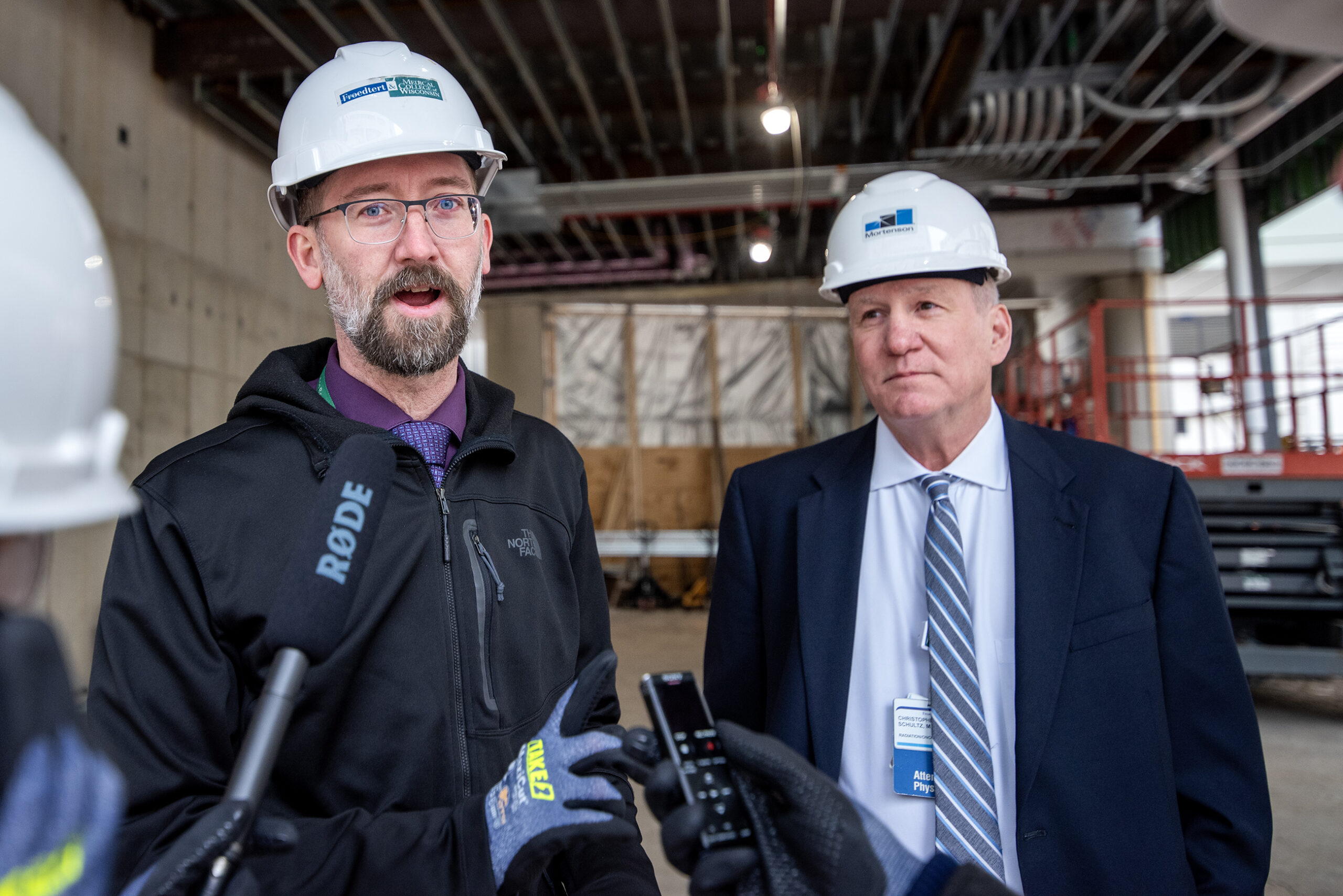 Two men in hard hats speak on the site.