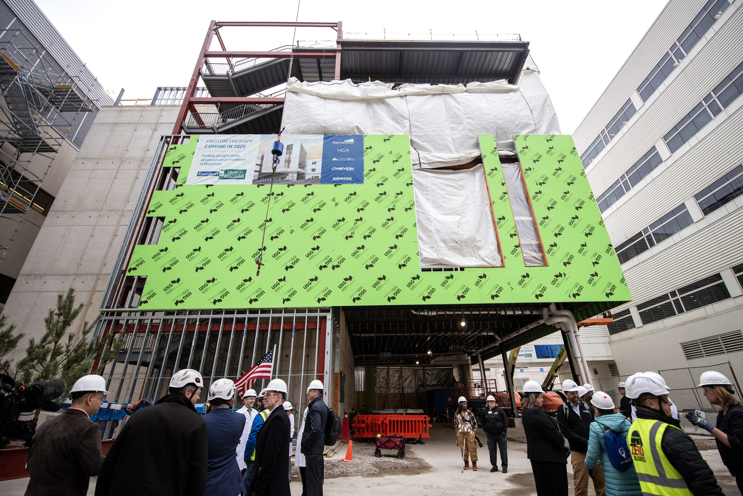 Green material covers the exterior of the building under construction