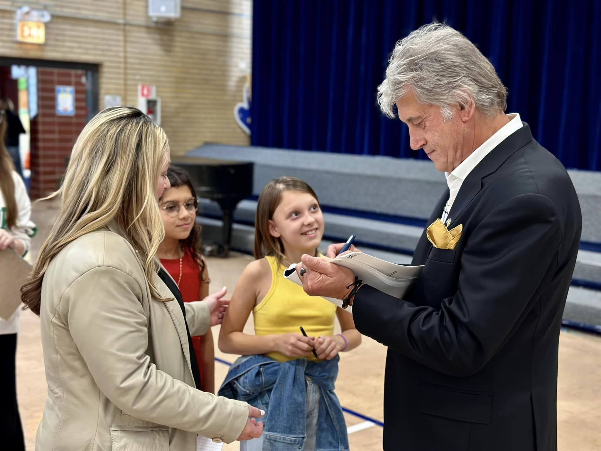 The former president of Ukraine signs an autograph as a student smiles at him.