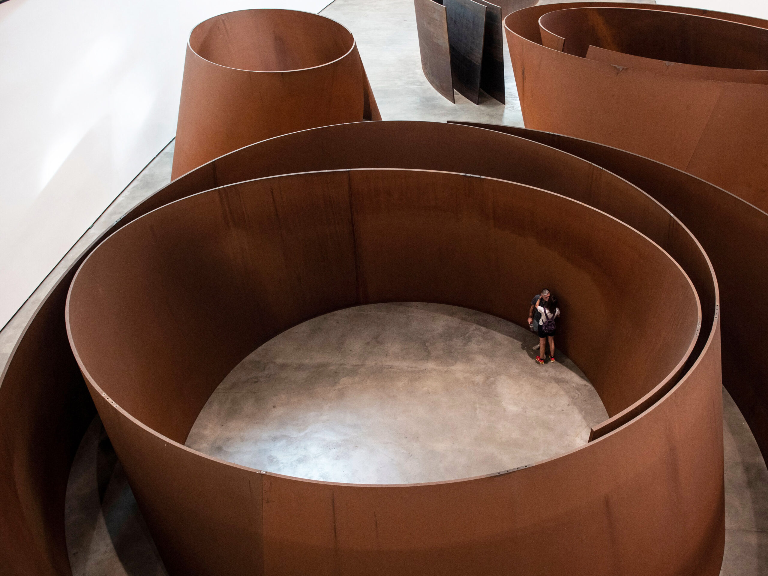Visitors look at the artwork "The Matter of Time" by US artist Richard Serra during the presentation of the "25 Years of the Museum Collection" exhibition on the 25th anniversary of the Guggenheim Museum Bilbao in the Spanish Basque city of Bilbao on Oct. 18, 2022.