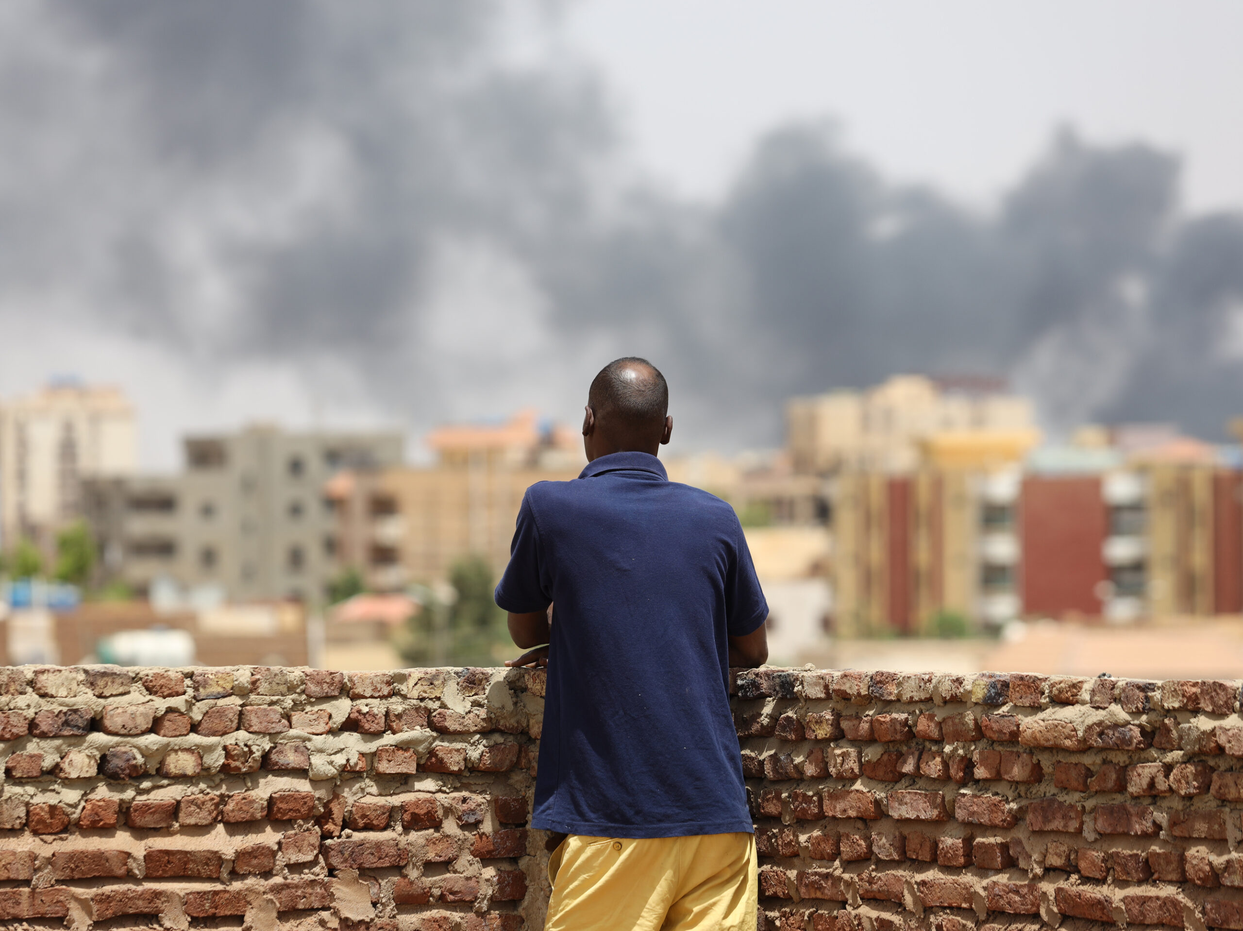 A man looks at the smoke rising next to the Army General Command in Khartoum, Sudan, on April 16, 2023.