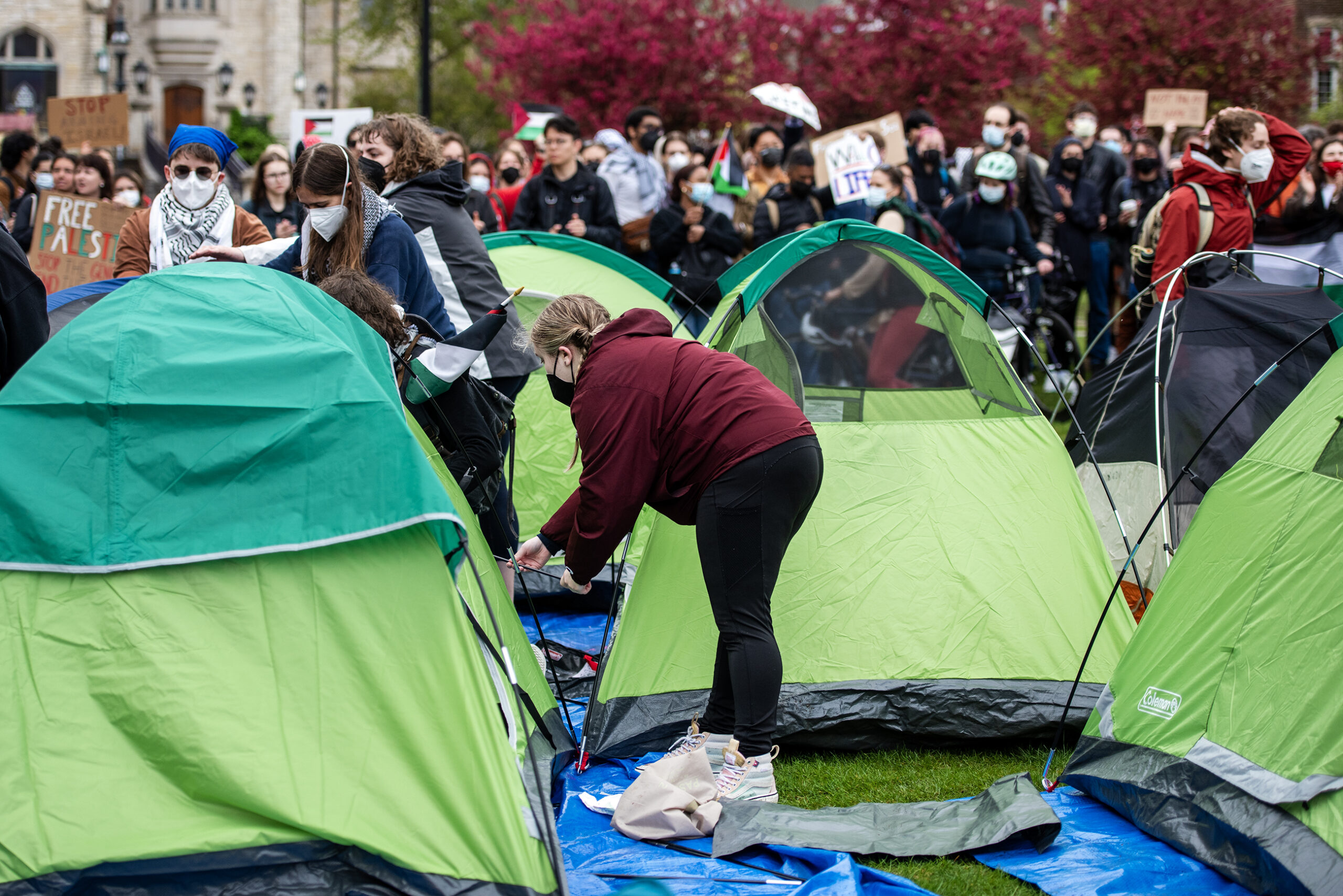 Green tents are pitched in the crowd of protesters.