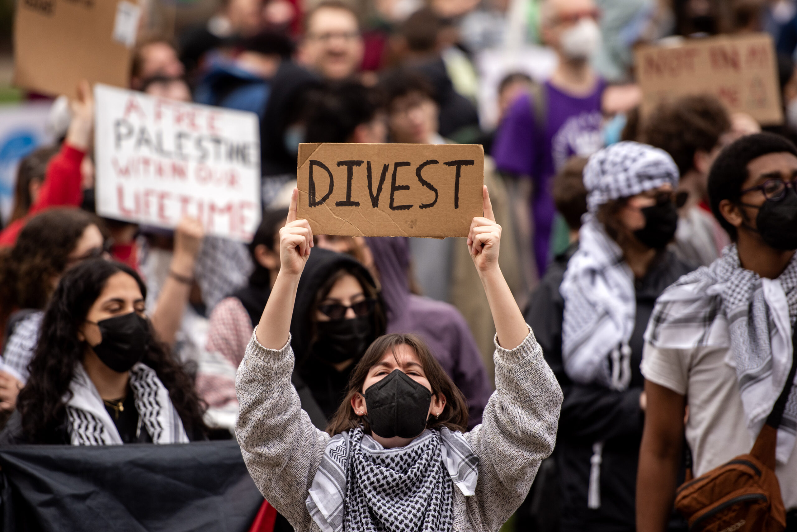A woman holds a sign that says "DIVEST."