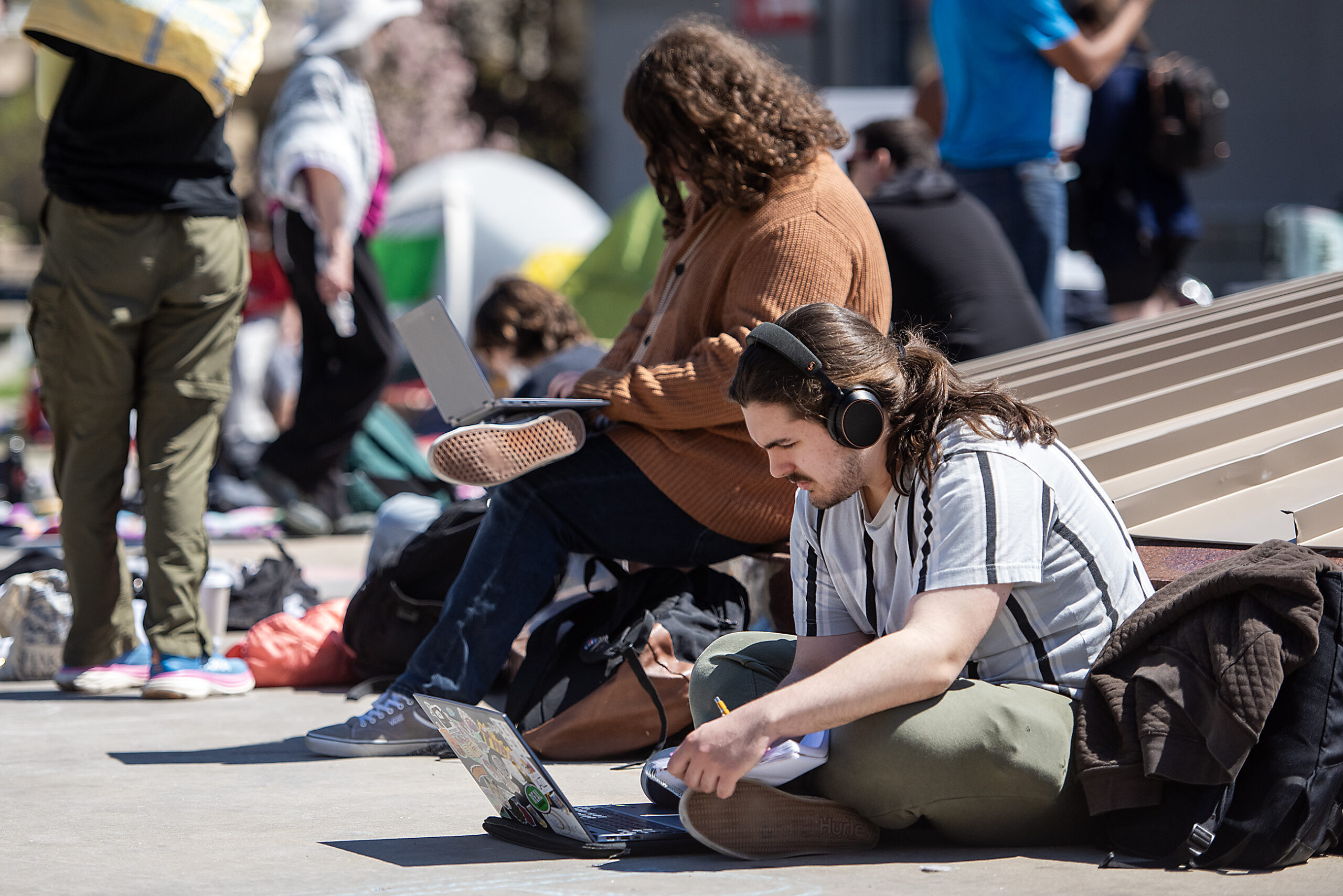 A person sits on the ground and uses a laptop.