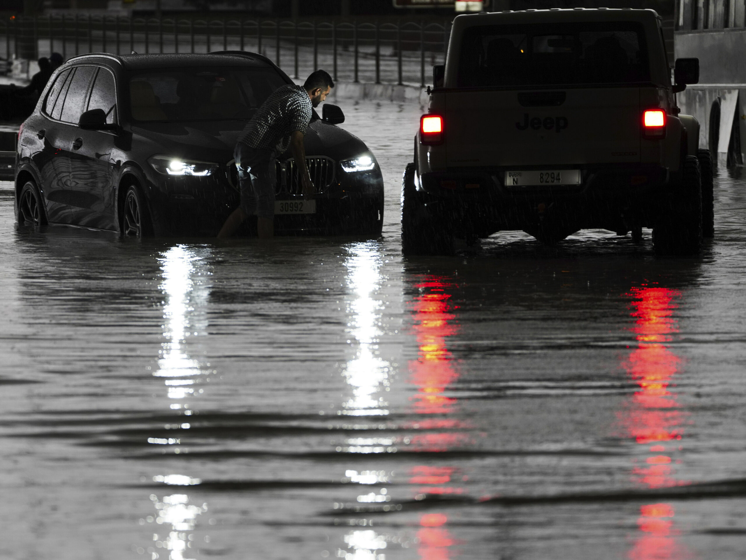 A man tries to work on his stalled SUV in standing water in Dubai, United Arab Emirates, on Tuesday.
