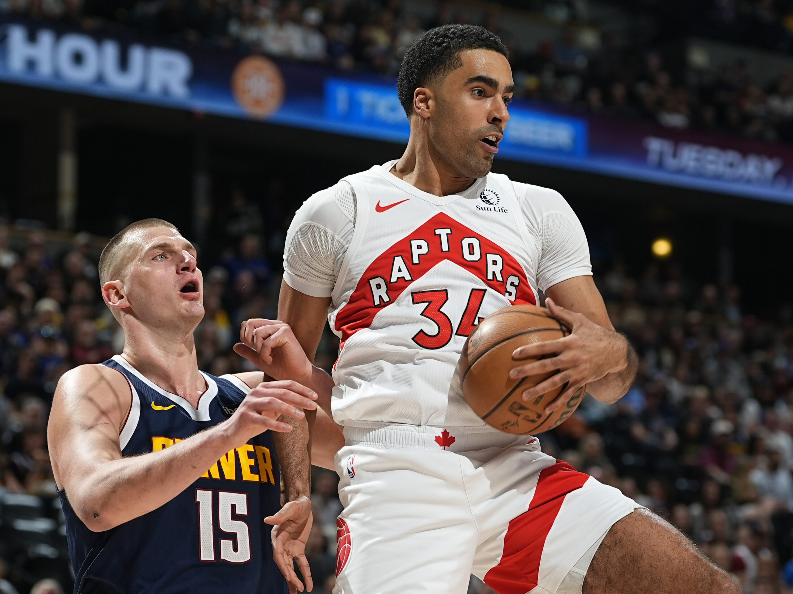 Toronto Raptors center Jontay Porter (right) pulls in a rebound as Denver Nuggets center Nikola Jokic defends in an NBA game on March 11 in Denver. On Wednesday, the NBA banned Porter after a league probe found he disclosed confidential information to sports bettors and bet on games.