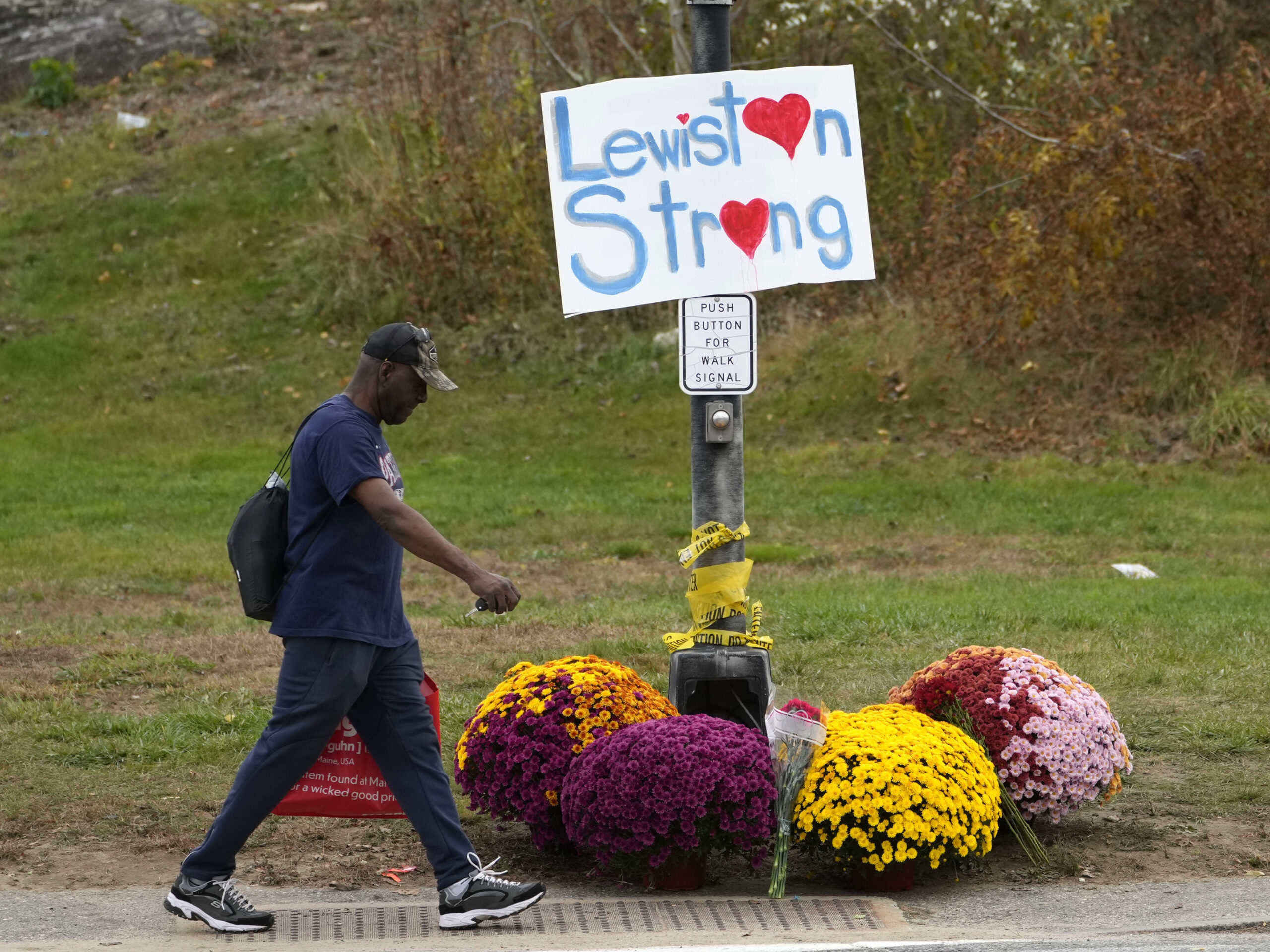 A man walks by flowers and a sign of support for the community, Oct. 28, 2023, in the wake of the mass shootings that occurred on in Lewiston, Maine. The Maine Legislature on Thursday approved sweeping gun safety legislation nearly six months after the deadliest shooting in state history.