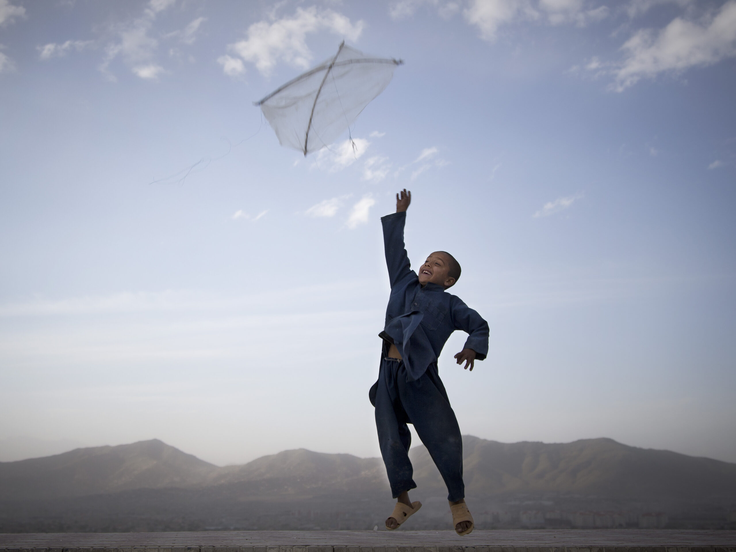 In this photo made by Associated Press photographer Anja Niedringhaus, an Afghan boy flies his kite on a hill overlooking Kabul, Afghanistan, May 13, 2013.