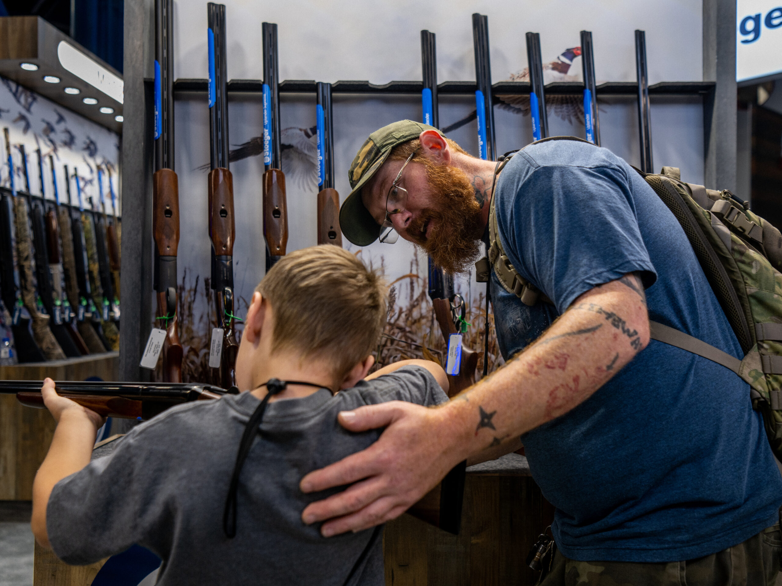 A father helps his son steady a firearm at the National Rifle Association (NRA) annual convention on May 28, 2022, in Houston, Texas. Exposing children to guns comes with risks, but some firearms enthusiasts say they'd prefer to train kids to use guns responsibly.