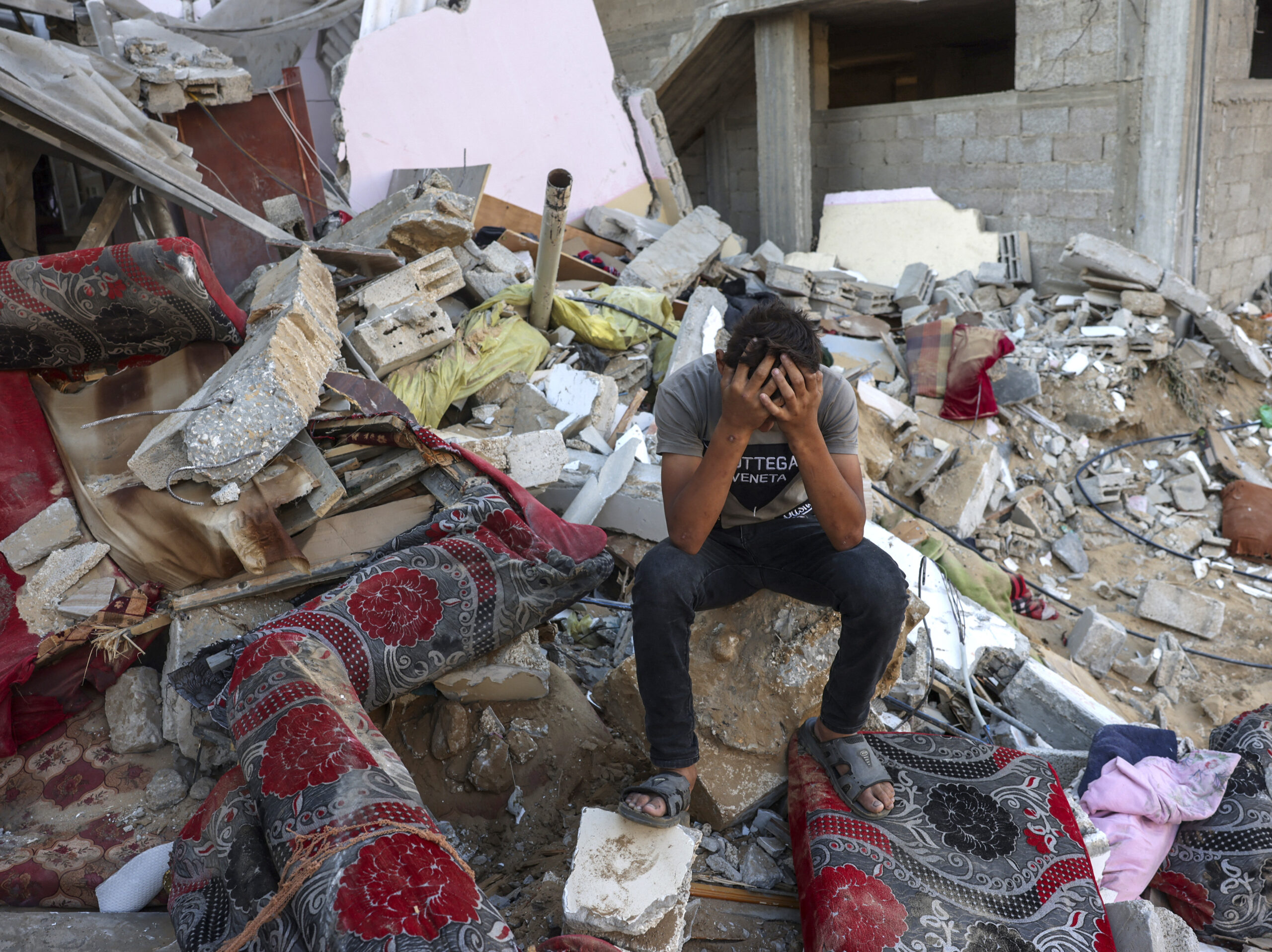 A young Palestinian sits on the rubble of a destroyed home following an Israeli military strike on the Rafah refugee camp, in the southern of Gaza Strip, on Oct. 15. Sunday marks six months since the start of the war between Israel and Hamas.
