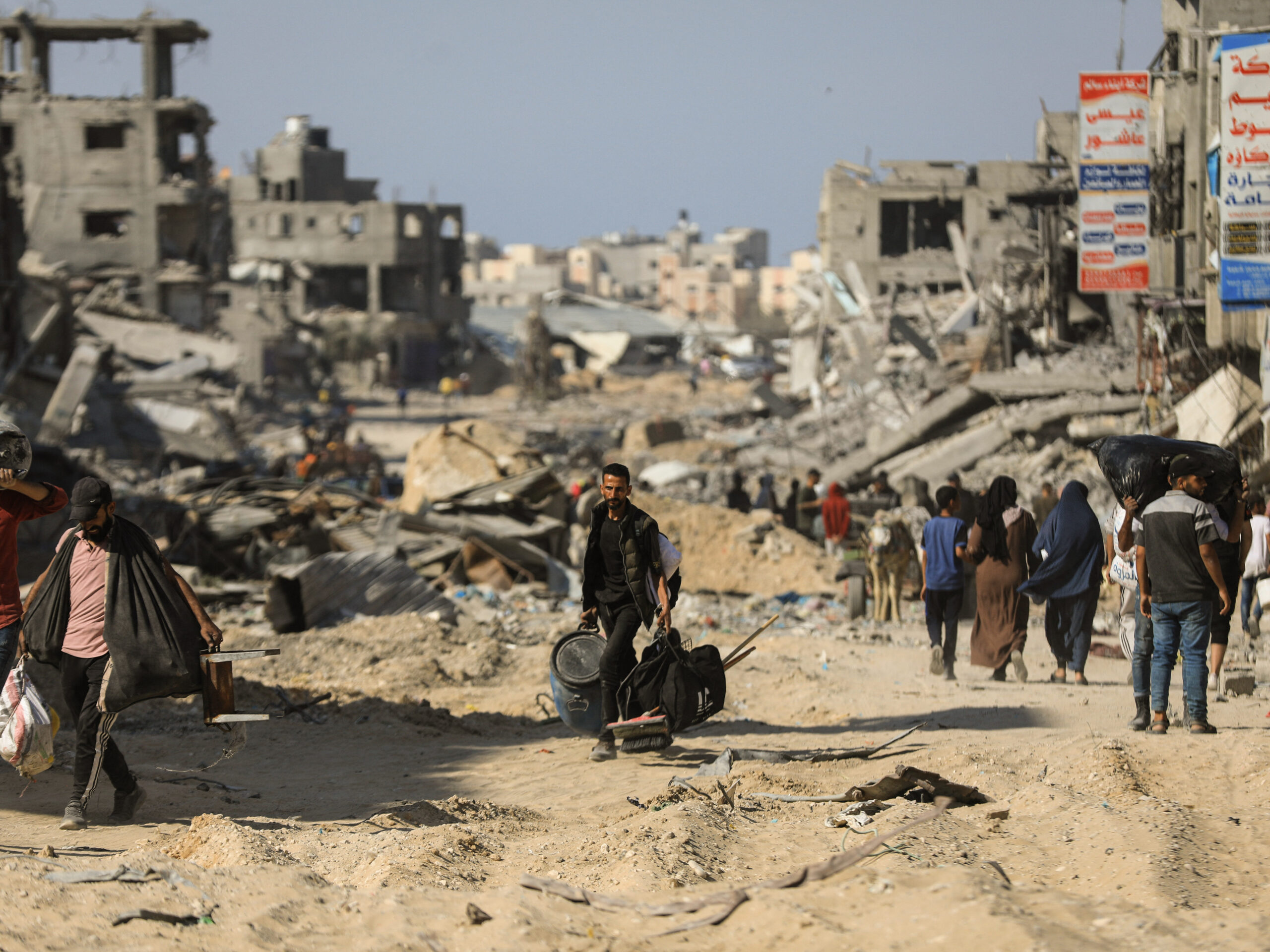 People walk past destroyed buildings along a road in Khan Younis on April 7, 2024 after Israel pulled its ground forces out of the southern Gaza Strip, six months into the war sparked by the Oct. 7 attacks.