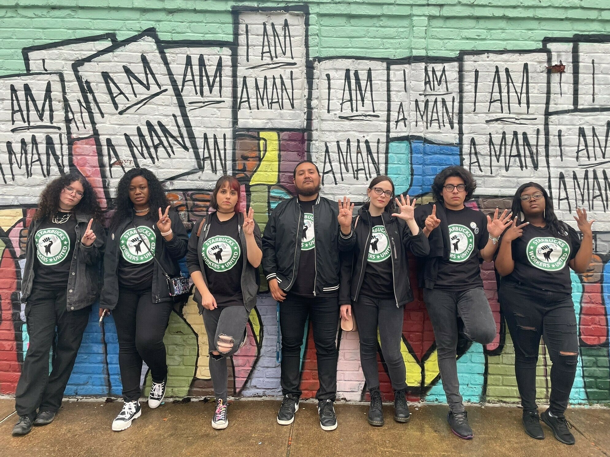 Florentino Escobar (second from right) and the six other Starbucks employees known together as the Memphis 7 stand in front of a Memphis, Tenn., mural that honors the 1968 Memphis sanitation workers strike.