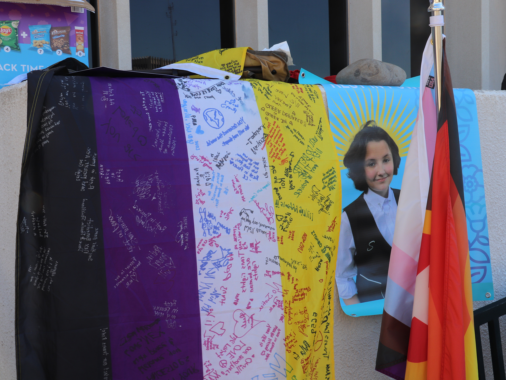 A portrait of Oklahoma teenager Nex Benedict, who died in March, hangs next to a nonbinary pride flag signed by demonstrators outside the Oklahoma State Department of Education last month.