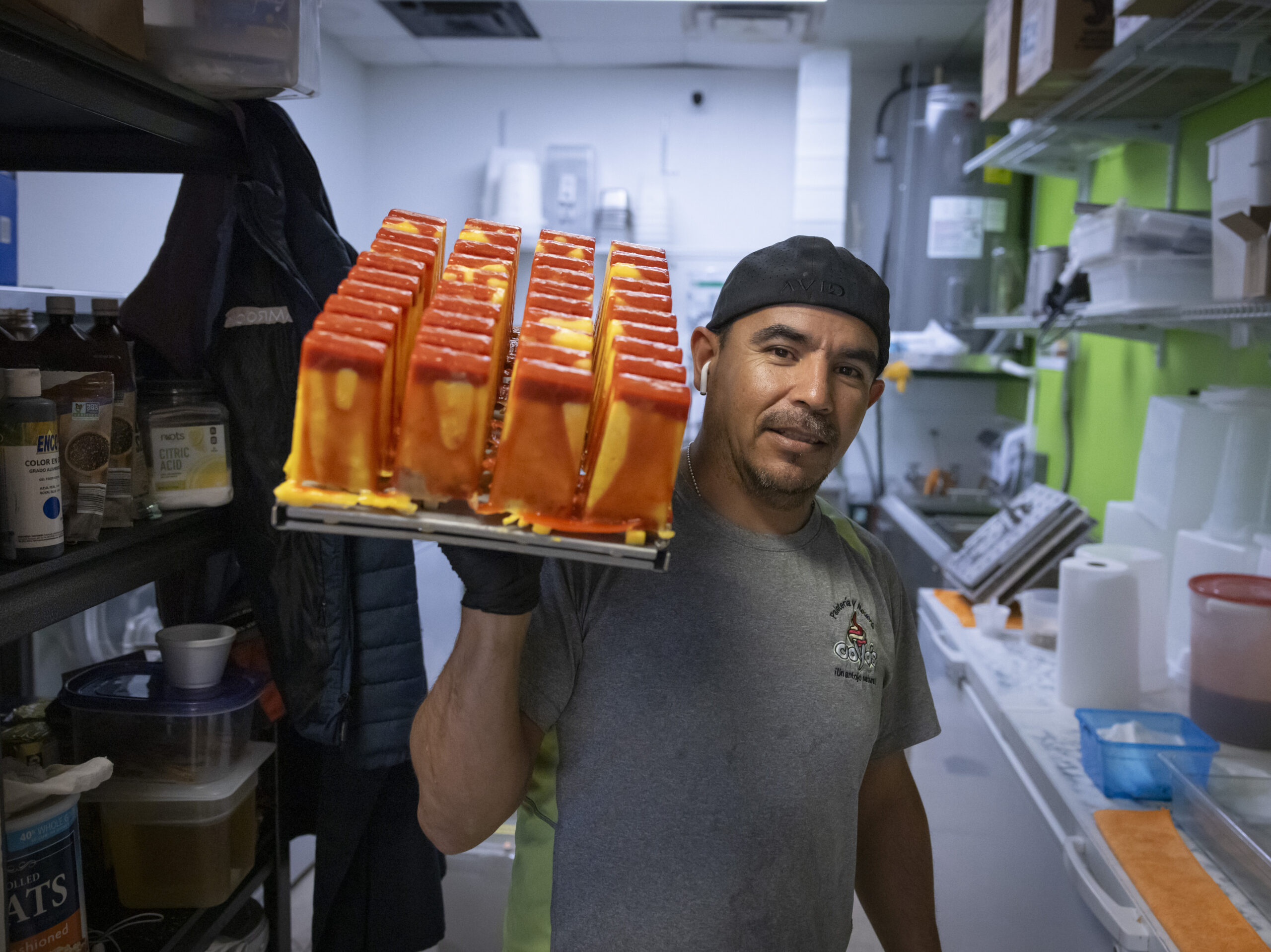 Manuel Vazquez, owner of Coya's artisan ice cream, poses for a photo as he carries a tray of ice pops in the kitchen of his shop in Fort Myers, Florida, U.S., February 26, 2024.
