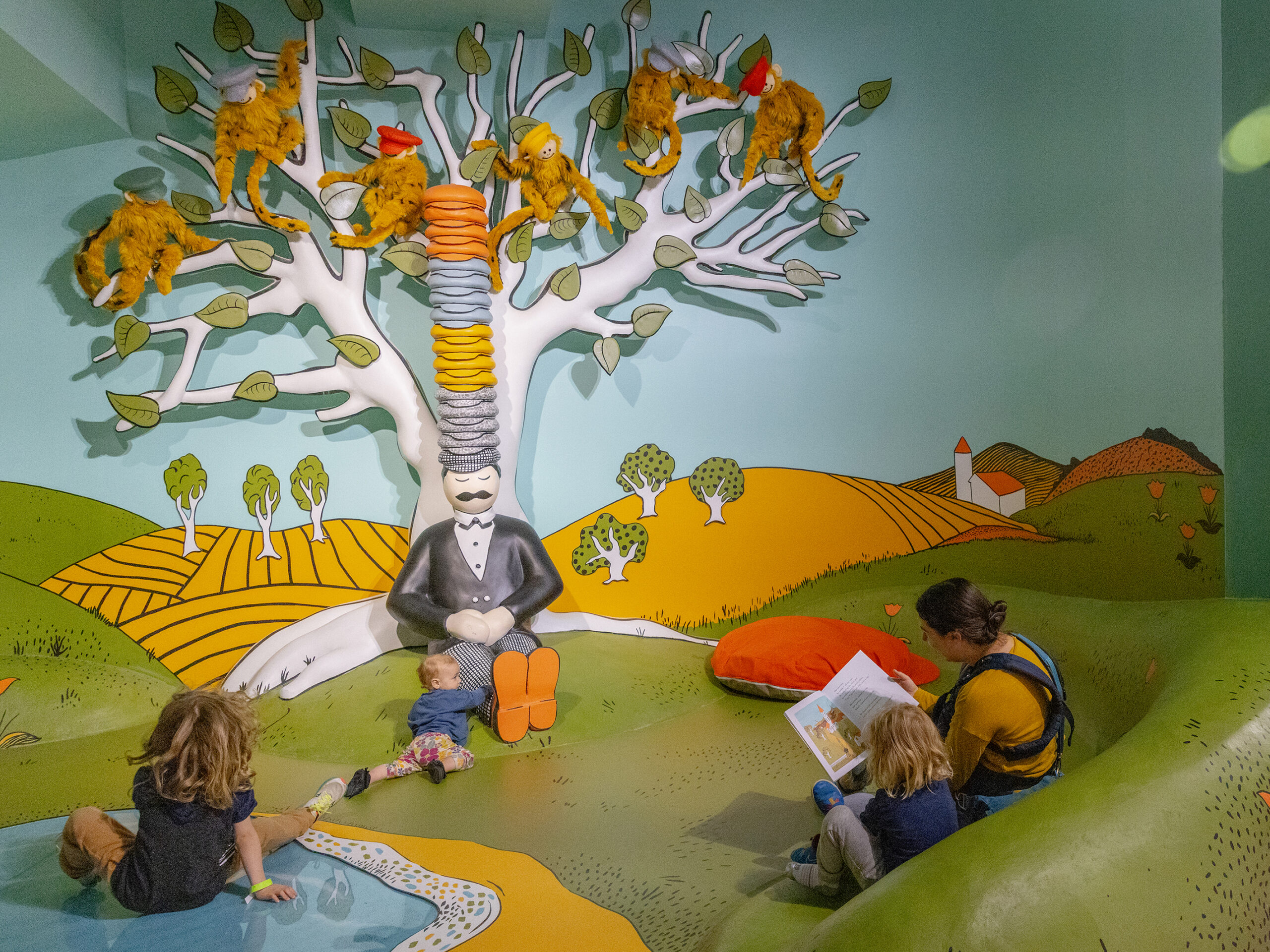 Lindsey Anderson sits down to read Caps for Sale by Esphyr Slobodkina to her children Orion, 6, Arthur, 4, and Thora Hoke, 1, inside the exhibit inspired by the book inside The Rabbit hOle, an immersive museum dedicated to children's literature, in North Kansas City, Mo.