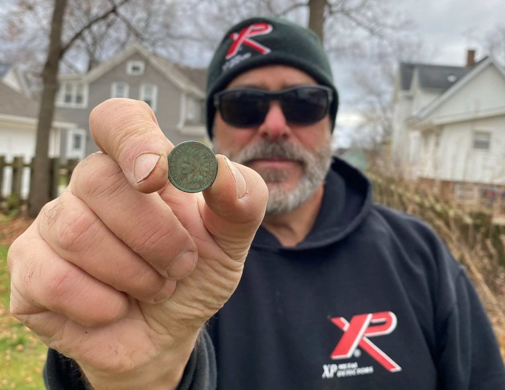 A metal detectorist holds an 1880 Indian Head penny.