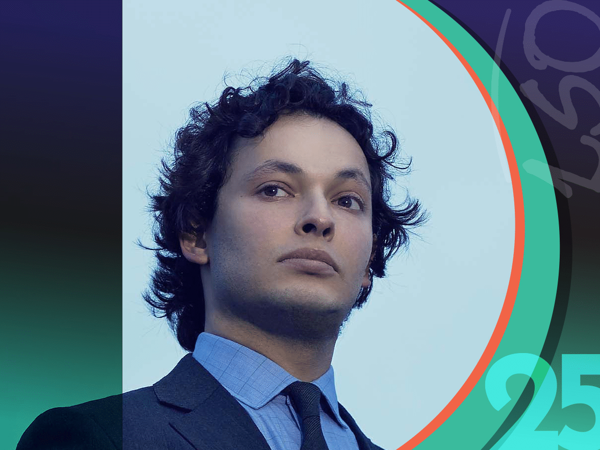 A person with curly dark hair wearing a suit and tie stands against a blue background with colorful graphic elements and the numbers 25 and 150.