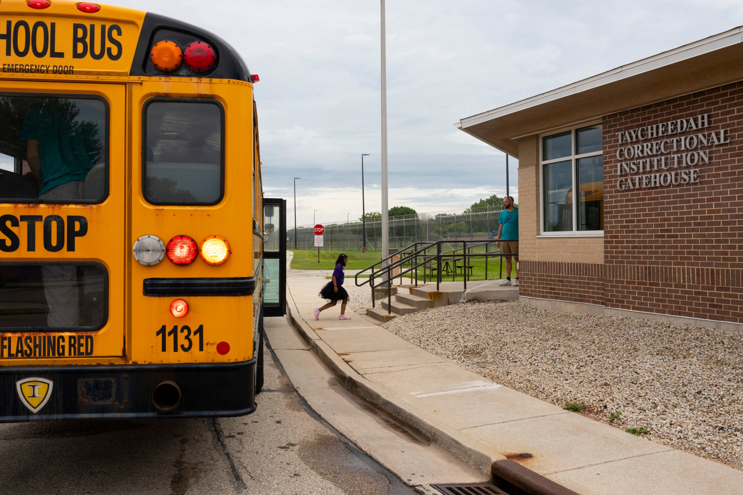A school bus is stopped outside the Taycheedah Correctional Institution Gatehouse as a child walks toward the building.