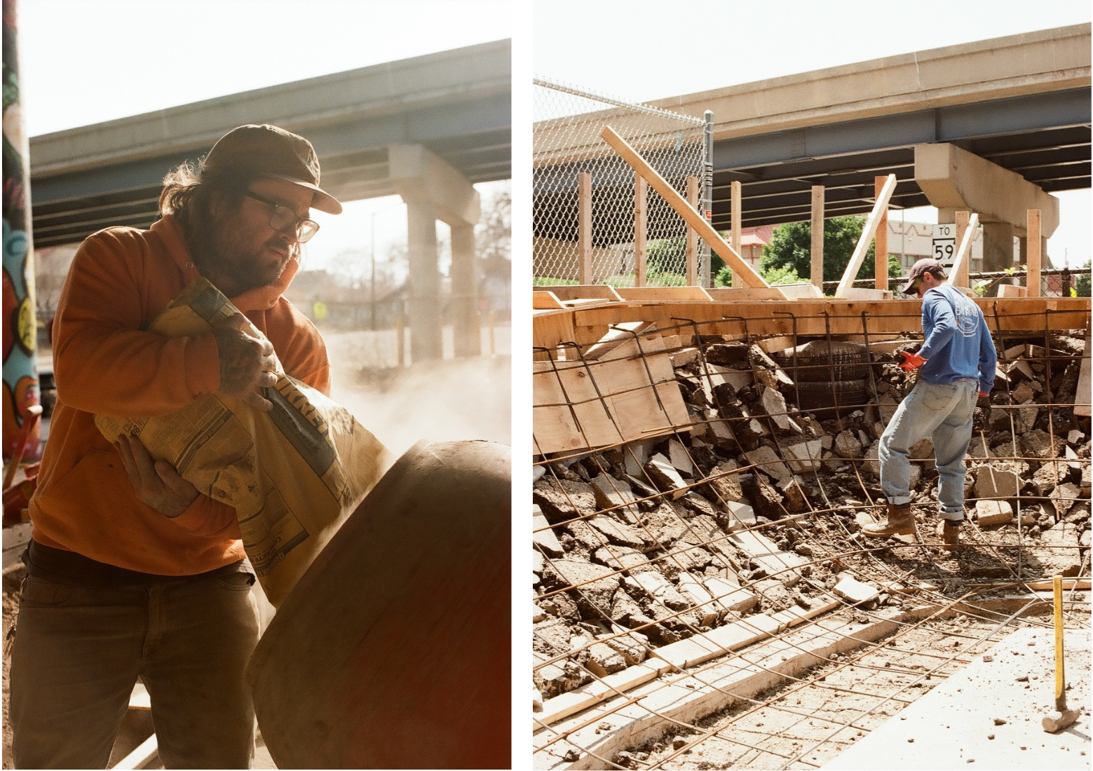 Two construction workers on a job site: one pouring material into a cement mixer, the other moving rocks near a wire and wood frame under a highway overpass.