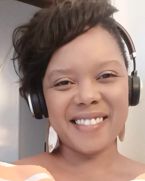 Morgan D. Stewart is smiling at the camera while wearing headphones and light-colored earrings.