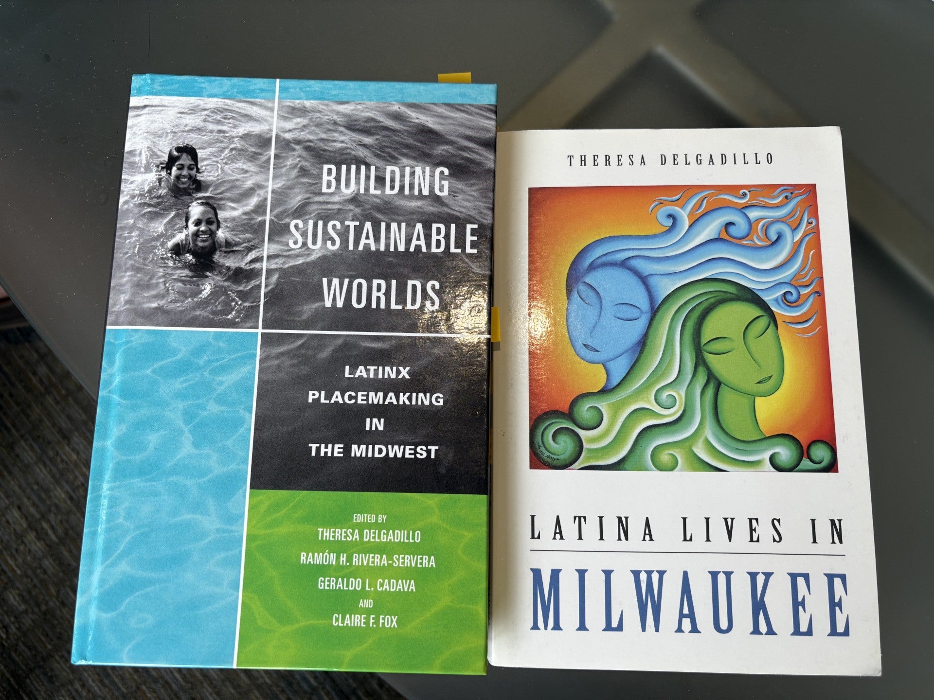 Two books are placed side by side on a table: Building Sustainable Worlds: Latinx Placemaking in the Midwest and Latina Lives in Milwaukee by Theresa Delgadillo.
