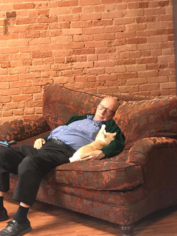 A man lying on a couch with a cat.