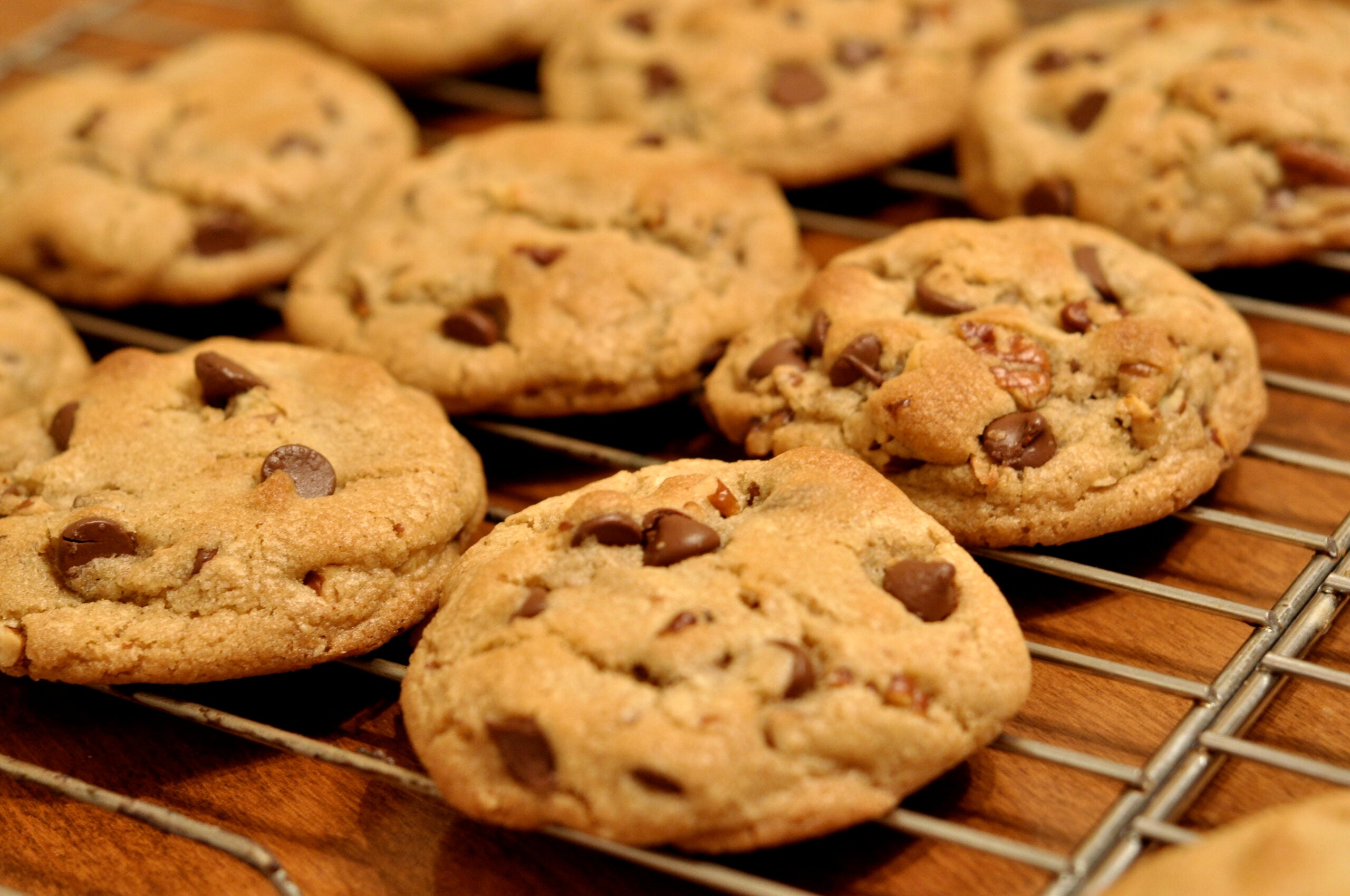 A batch of chocolate chip cookies cooling on a metal wire rack.
