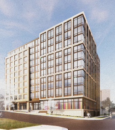 A modern multi-story building with large glass windows and grid-like framing, situated on a corner with a few people walking nearby.