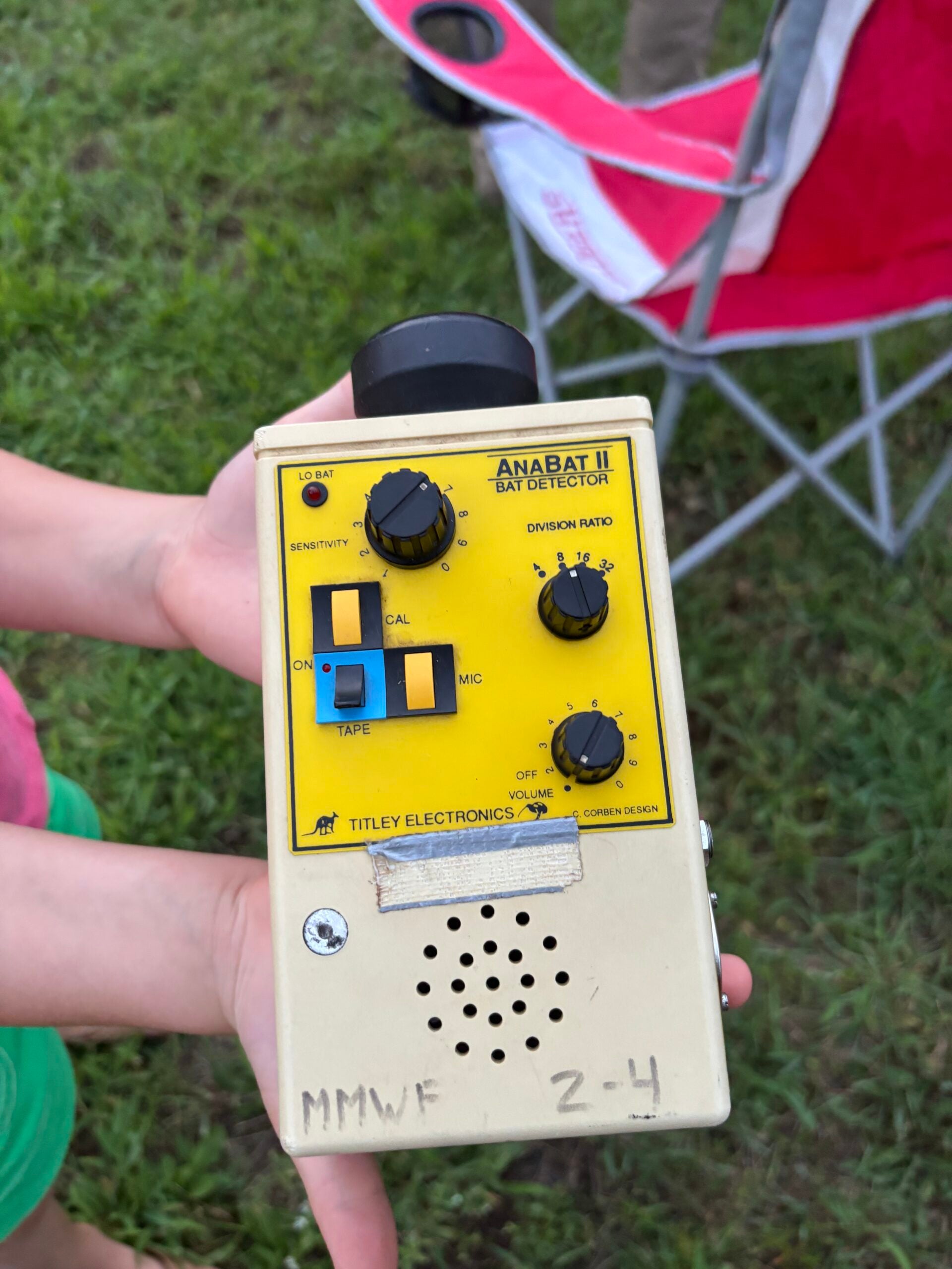 A person holds an ANABAT II bat detector by Titley Electronics, featuring a yellow control panel with knobs, switches, and tape labeled MMWF 2-4.