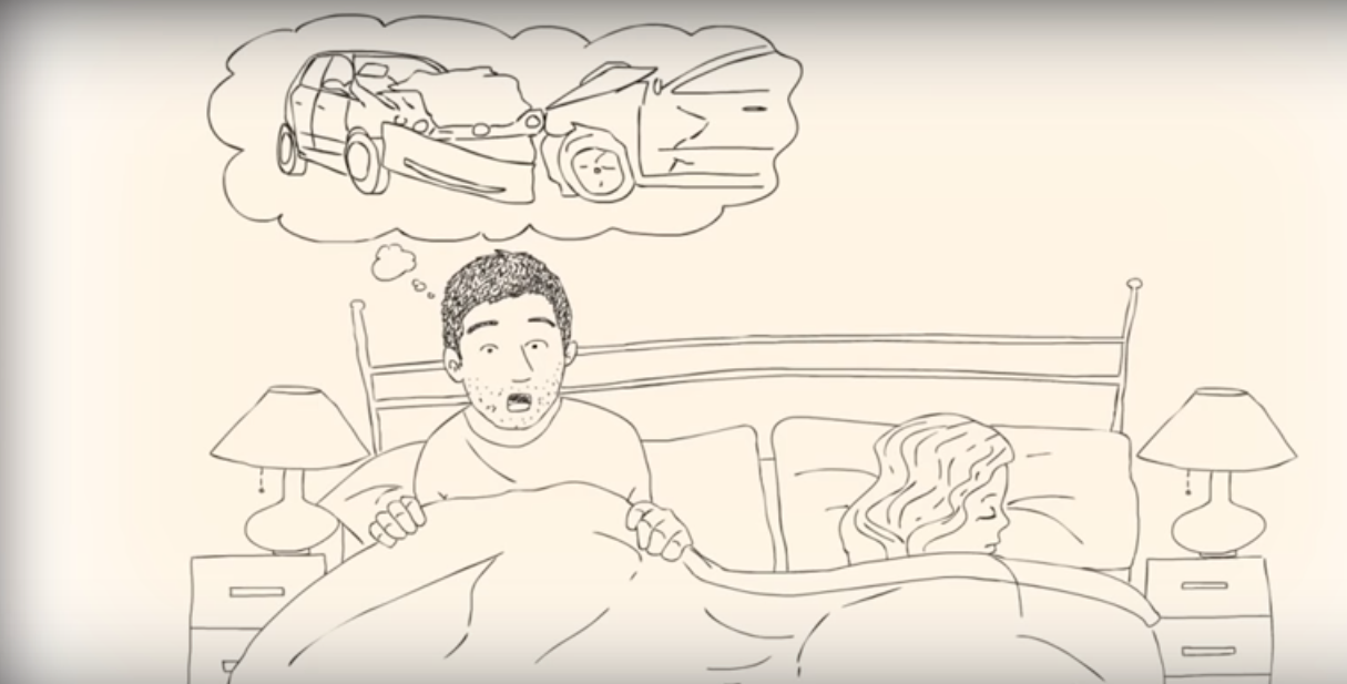 A man sits up in bed looking alarmed, with a thought bubble above his head depicting a car crash; a woman lies beside him asleep.