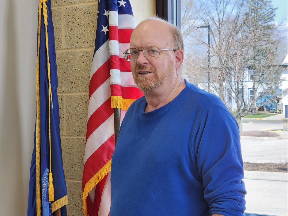 A man standing in front of a flag.